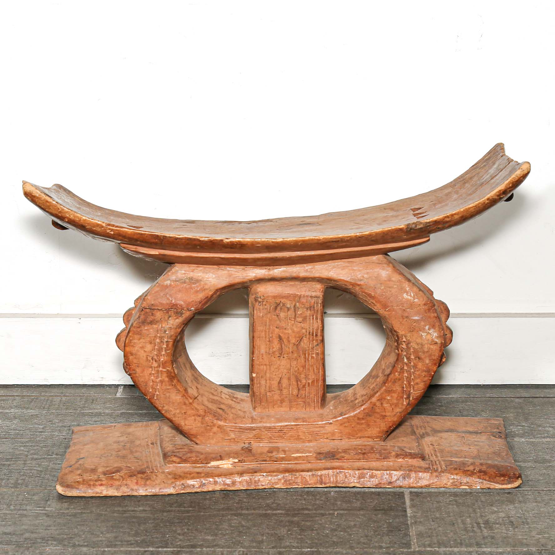 Wooden African table stool with curved top and base on a wooden floor used as bedroom African furniture 