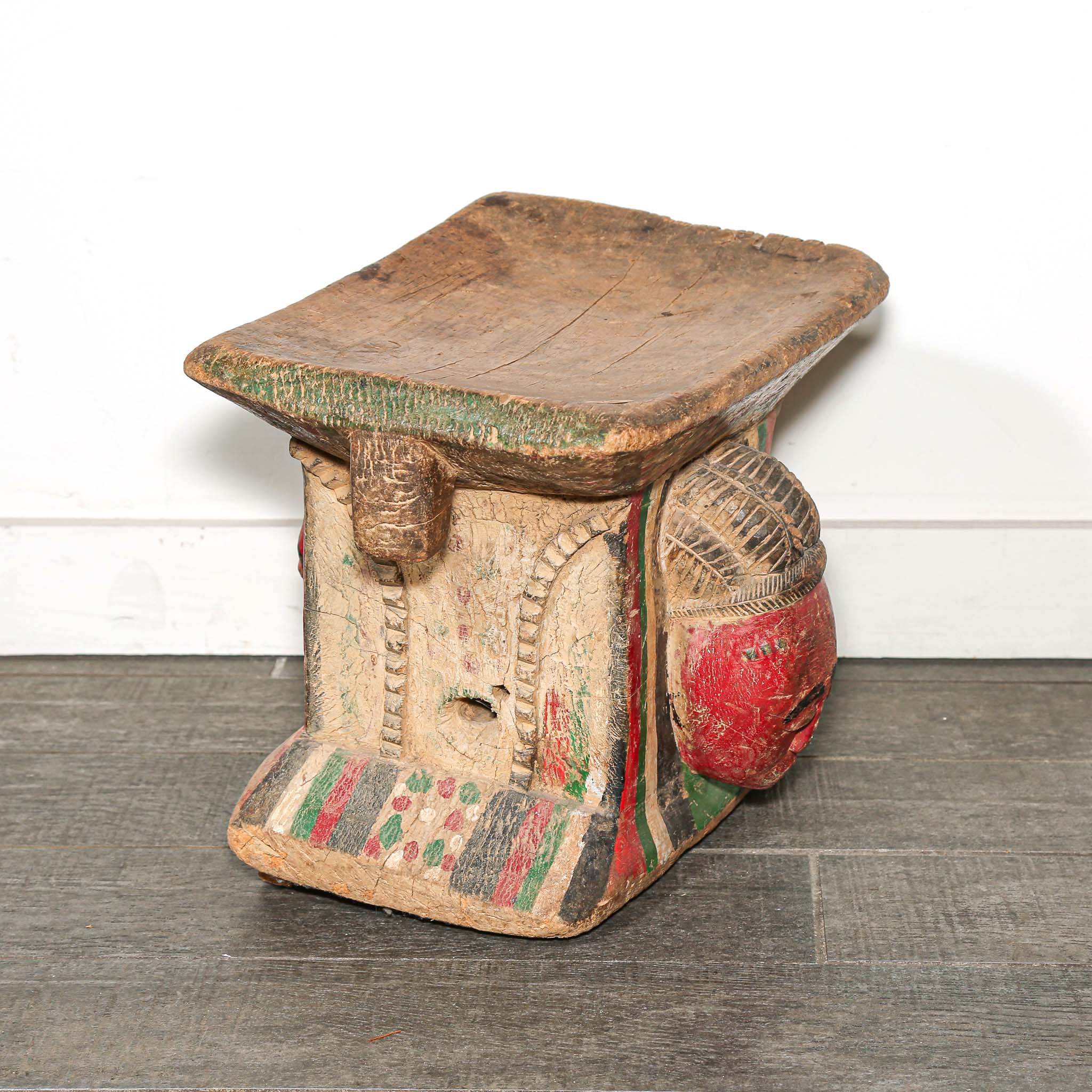 Vintage Wooden African stool with a red face design on a white background