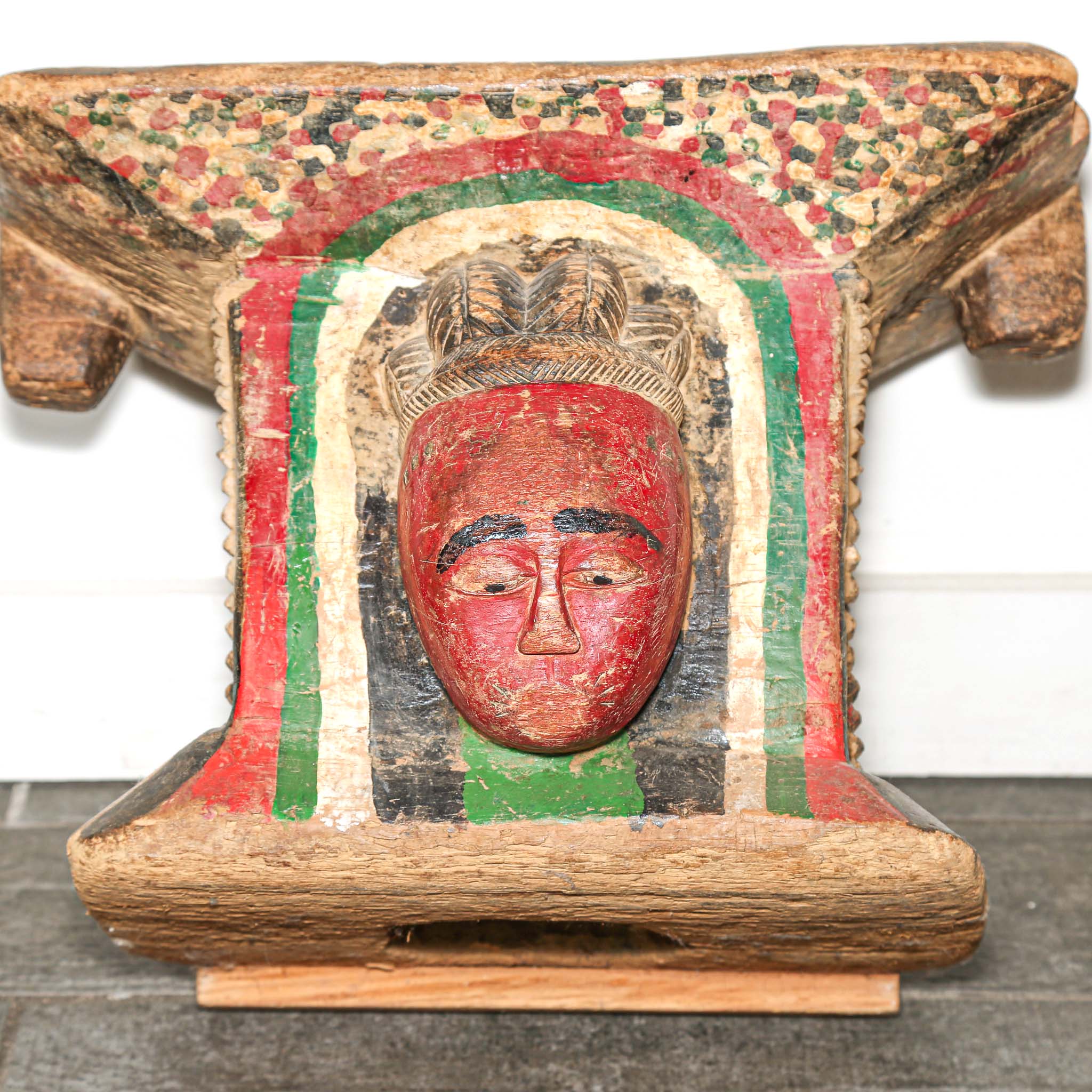 Vintage Wooden African stool with a red face design on a white background