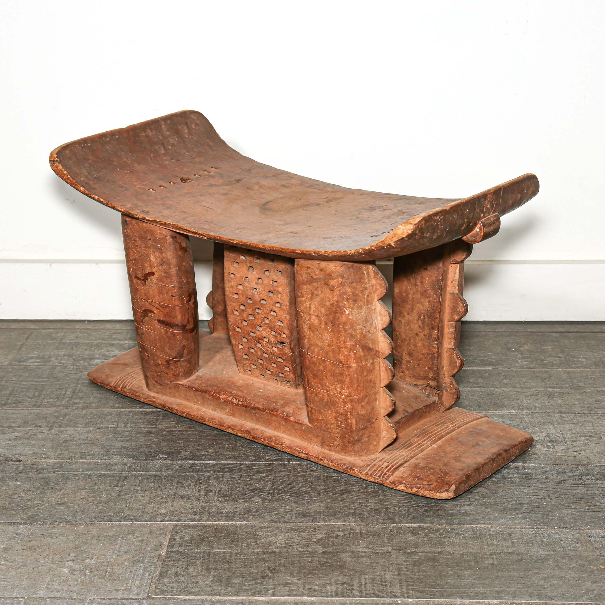 Wooden African vintage furniture with a curved backrest on a bedroom floor.