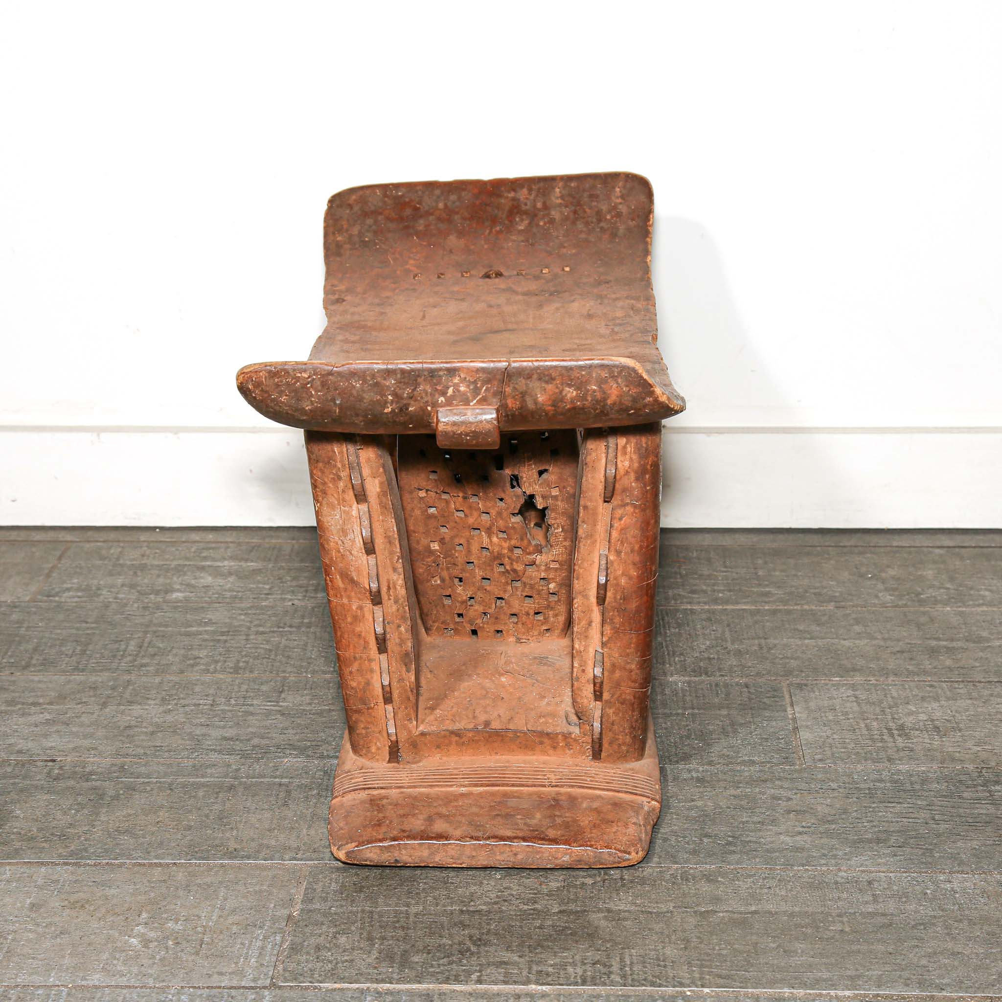 Wooden African vintage furniture with a curved backrest on a bedroom floor.