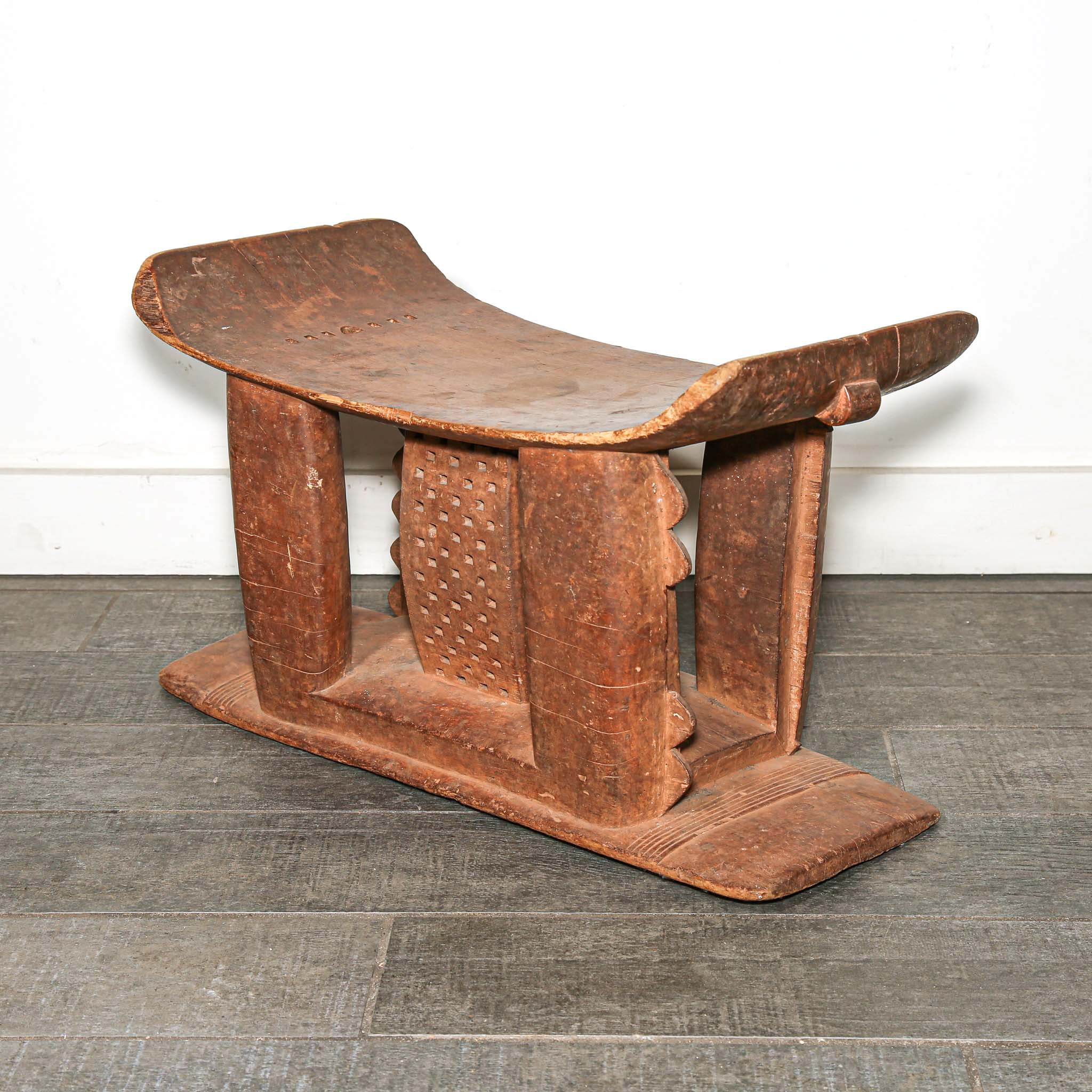 Wooden African vintage furniture with a curved backrest on a bedroom floor.