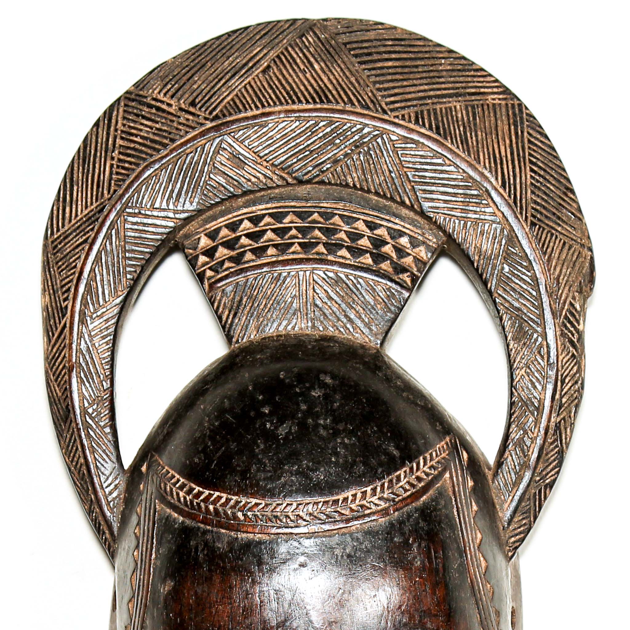 Finely carved wooden hand made african mask with intricate carvings on a white living room wall