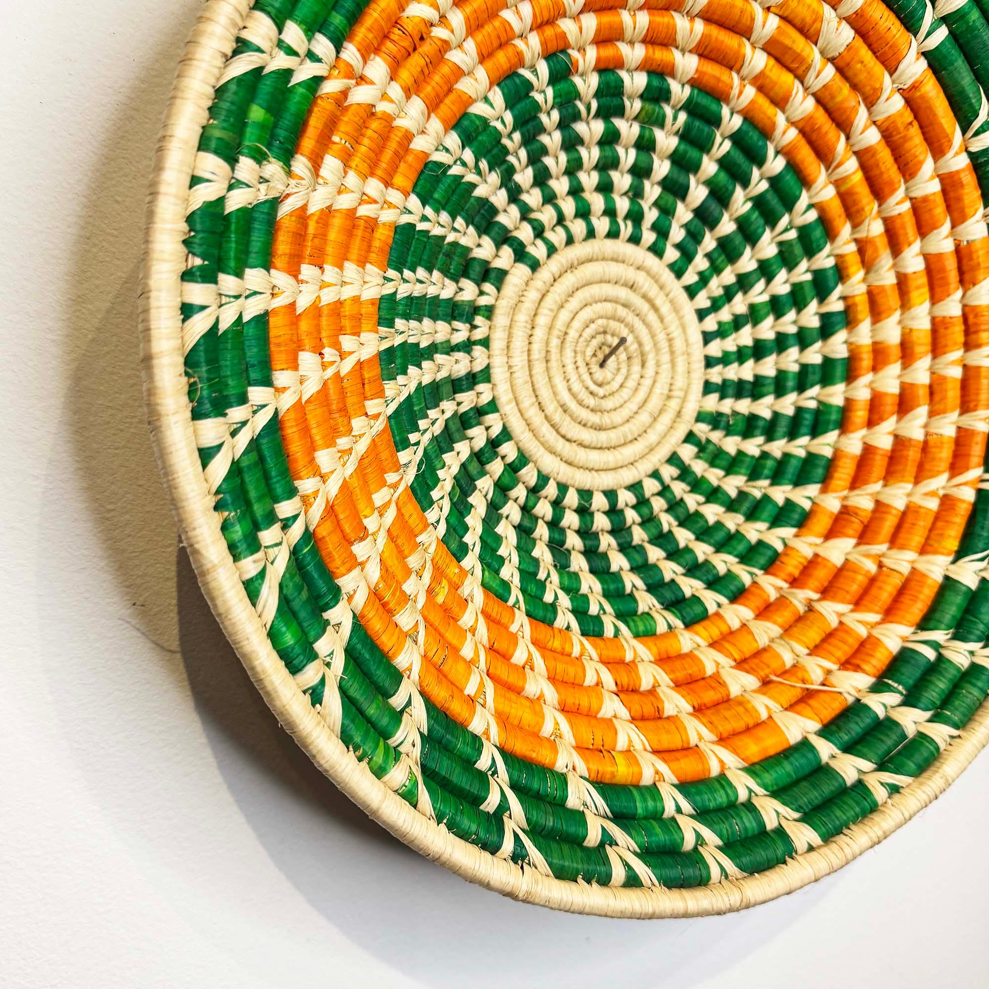 Green Woven Basket Handmade in Uganda hanging on a wall on a close up