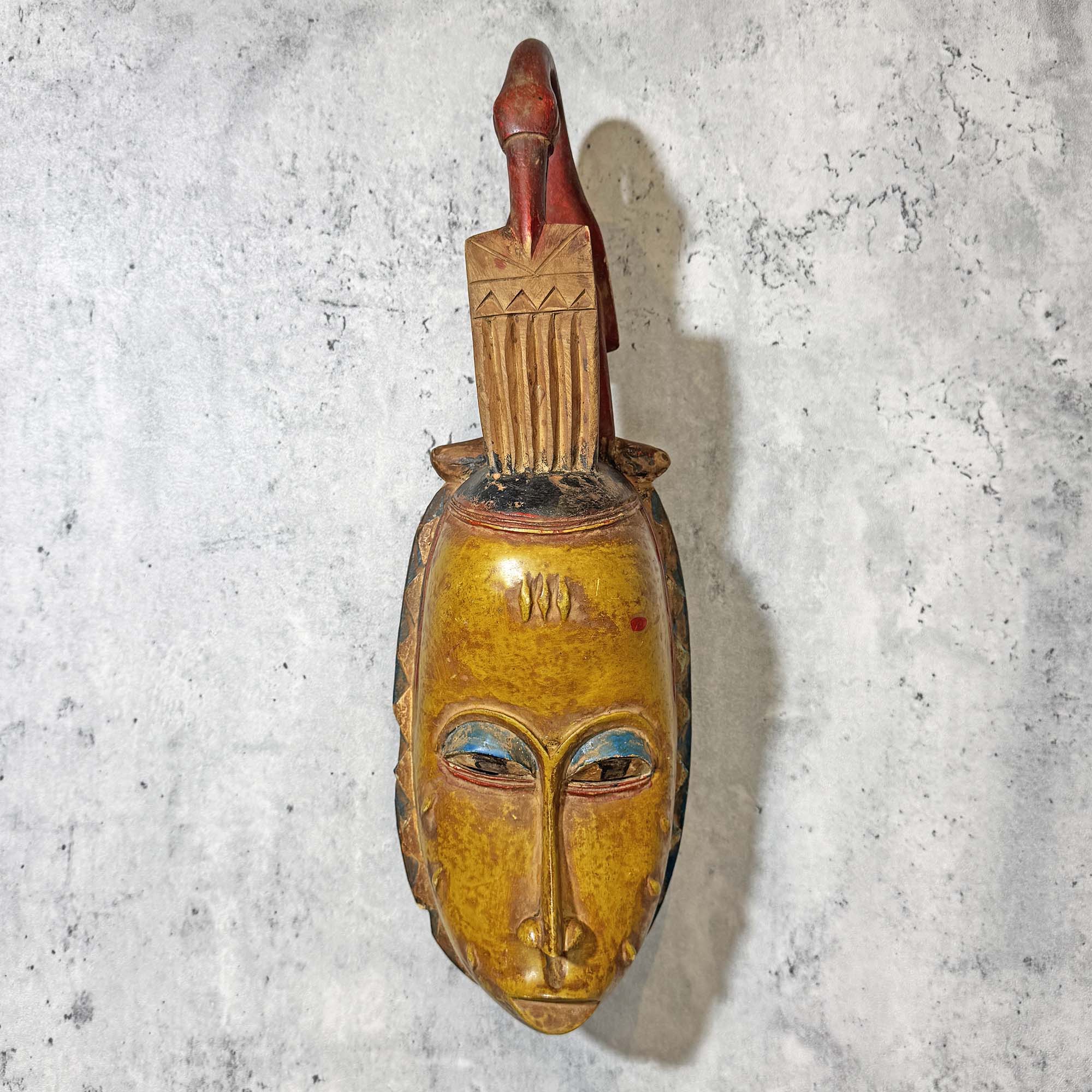 Guro Mask from Côte d'Ivoire Yellow-Red as an African mask wall decor idea in front