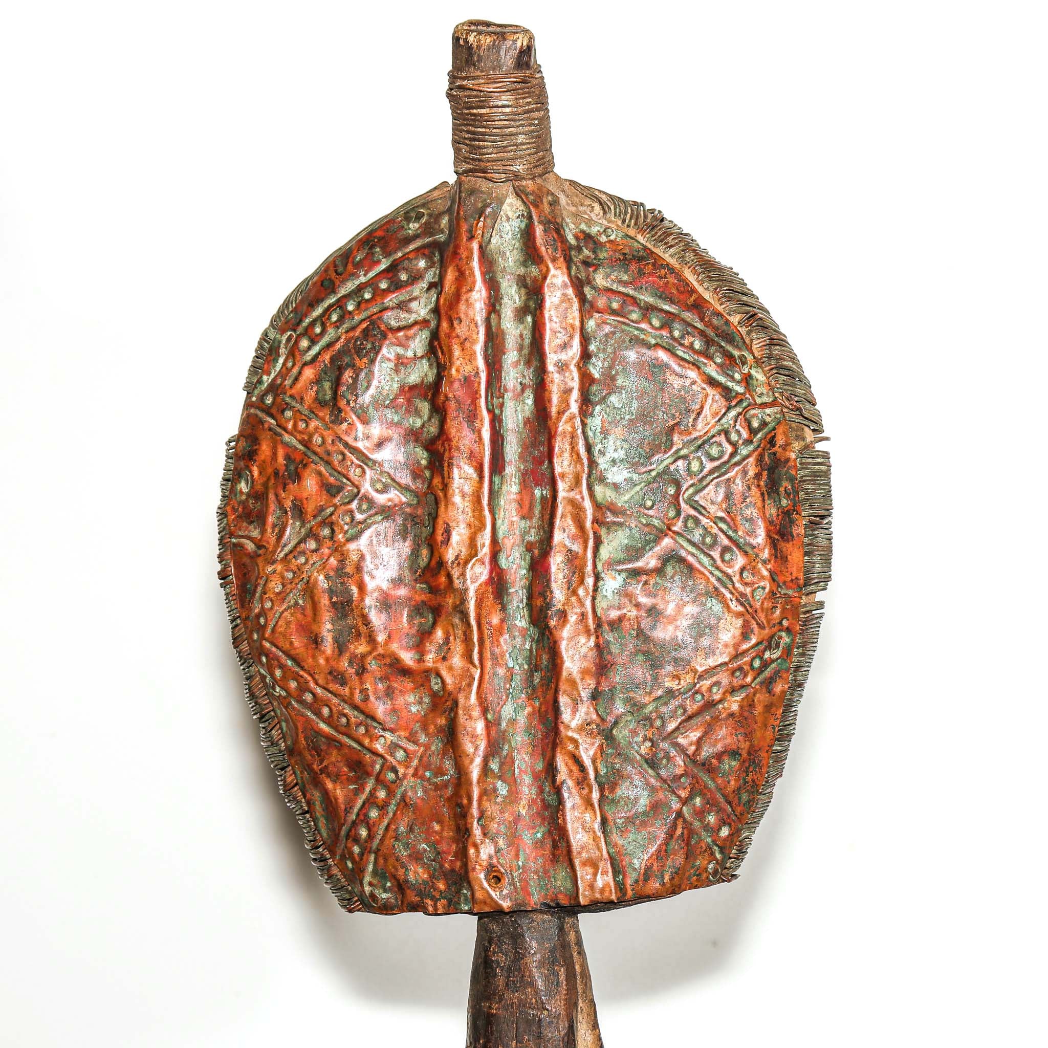 Wooden protective traditional mask from Gabon made from wood and metal on a round wooden table with a white background close up from behind