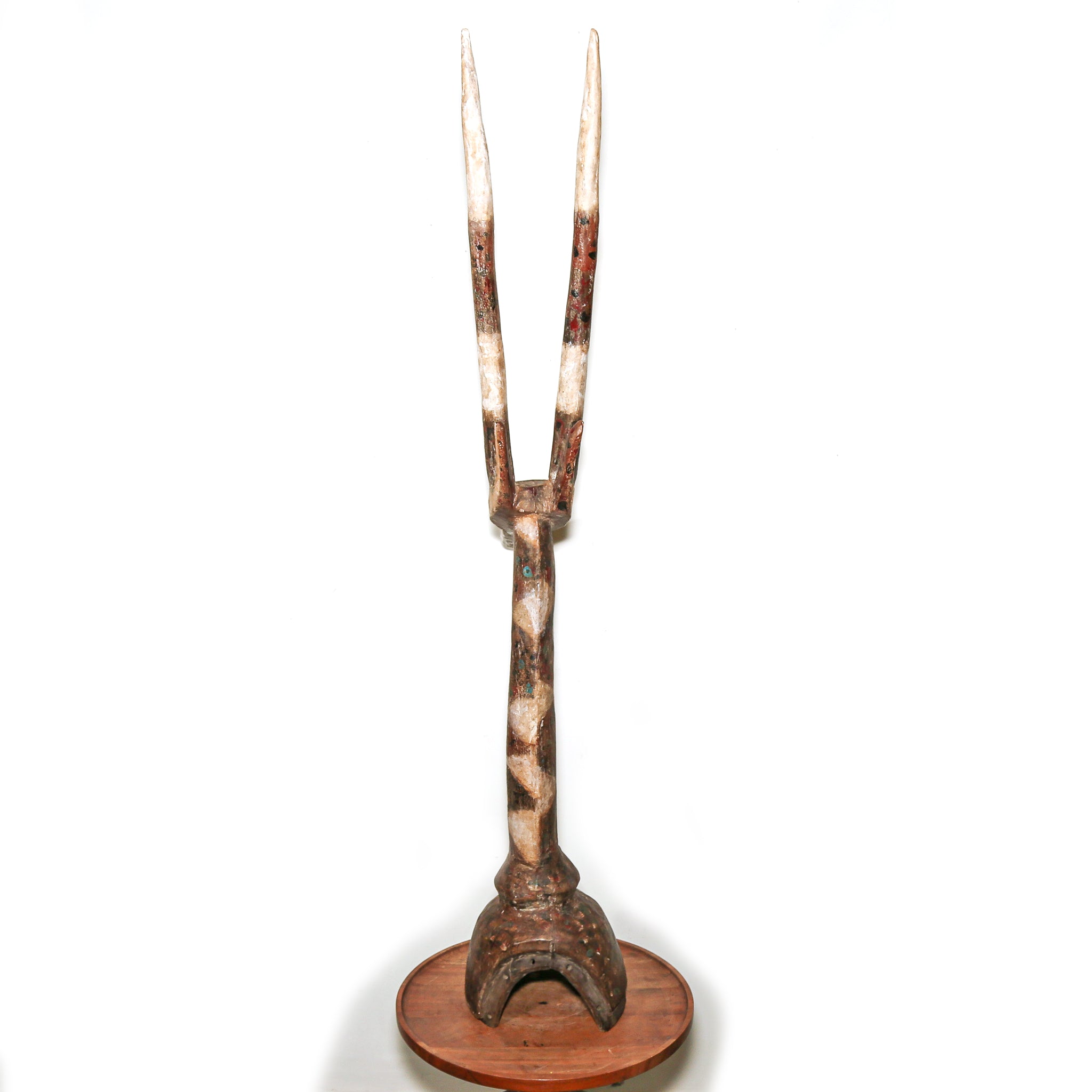 A carved wooden decorative African sculpture and a round wooden base, photographed against a plain white background.