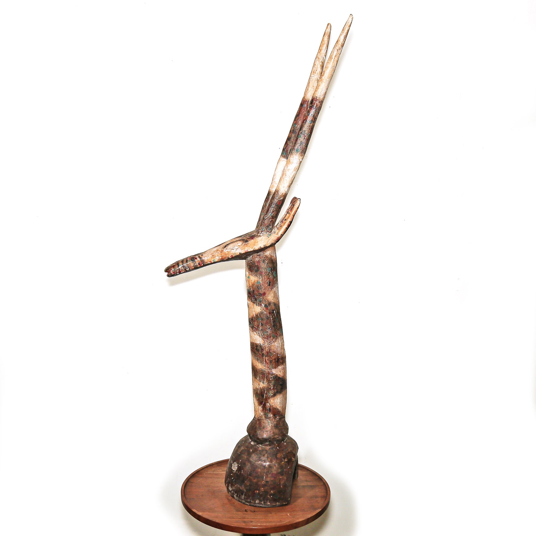 A handcrafted African-style horn sculpture on a circular wooden base, featuring natural horn patterns in brown, beige, and white, set against a plain white background.