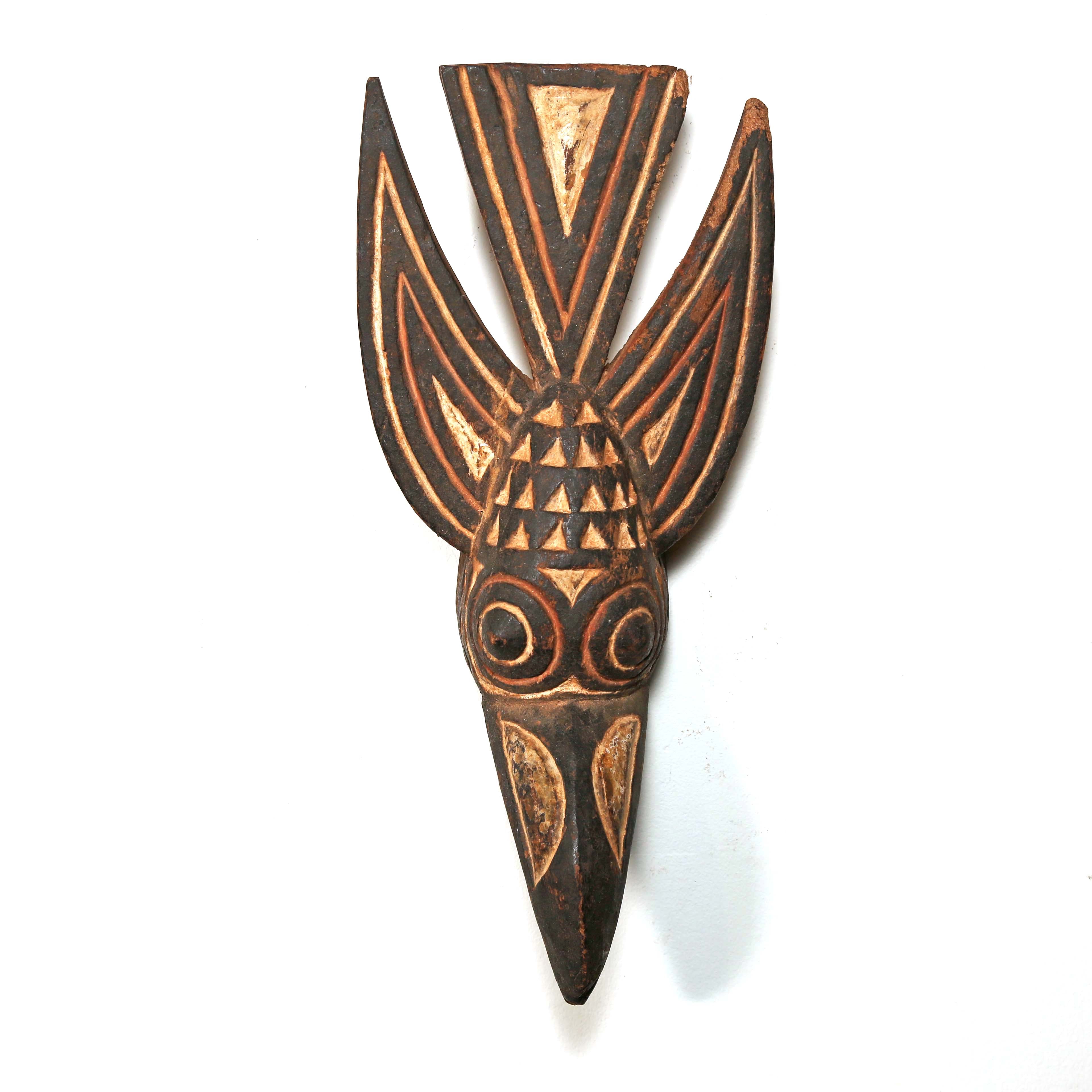 Decorative wooden wall hanging with tribal patterns in the shape of a bird from Africa on a white background