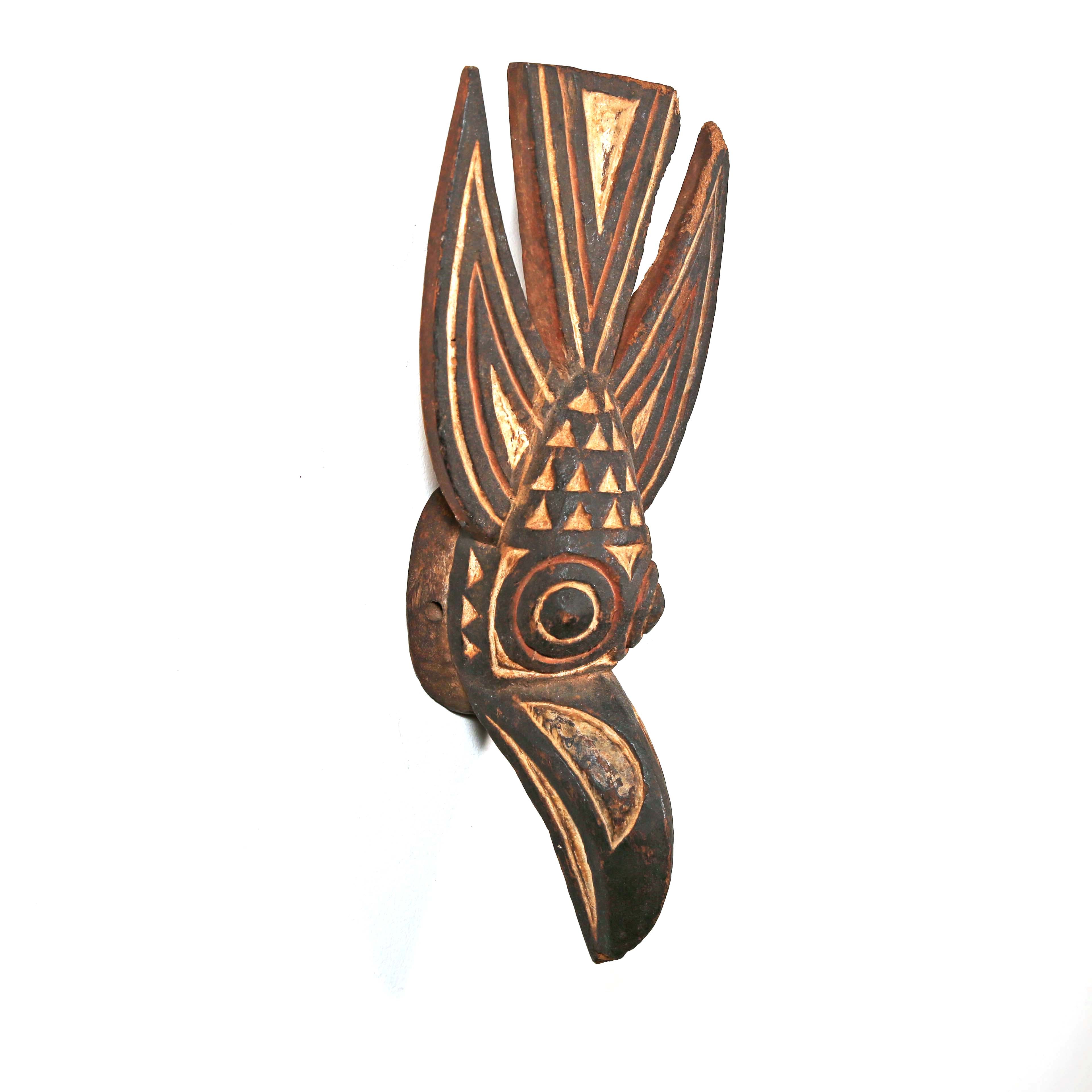 Decorative wooden wall hanging with tribal patterns in the shape of a bird from Africa on a white background