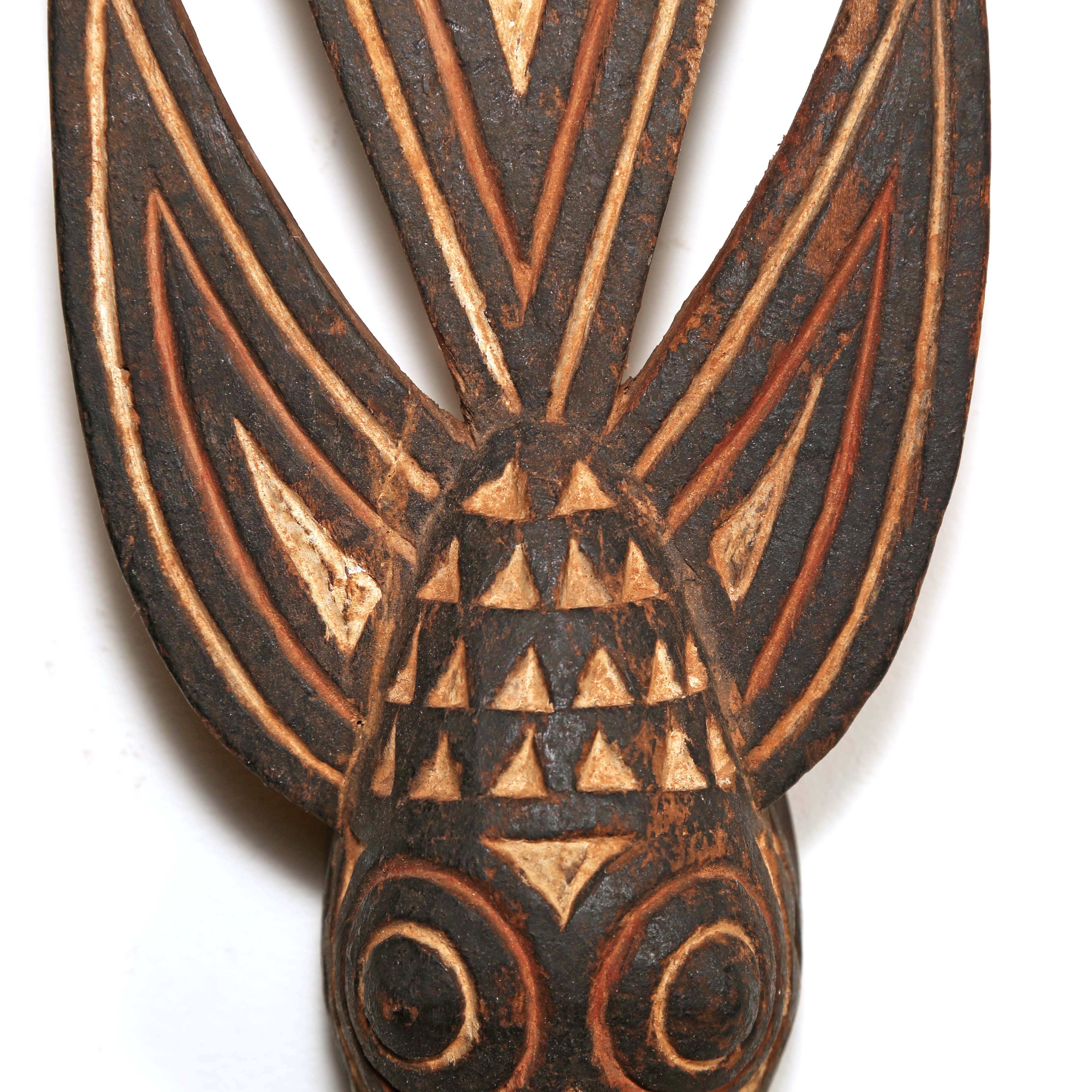 Decorative wooden wall hanging with tribal patterns in the shape of a bird from Africa on a white background