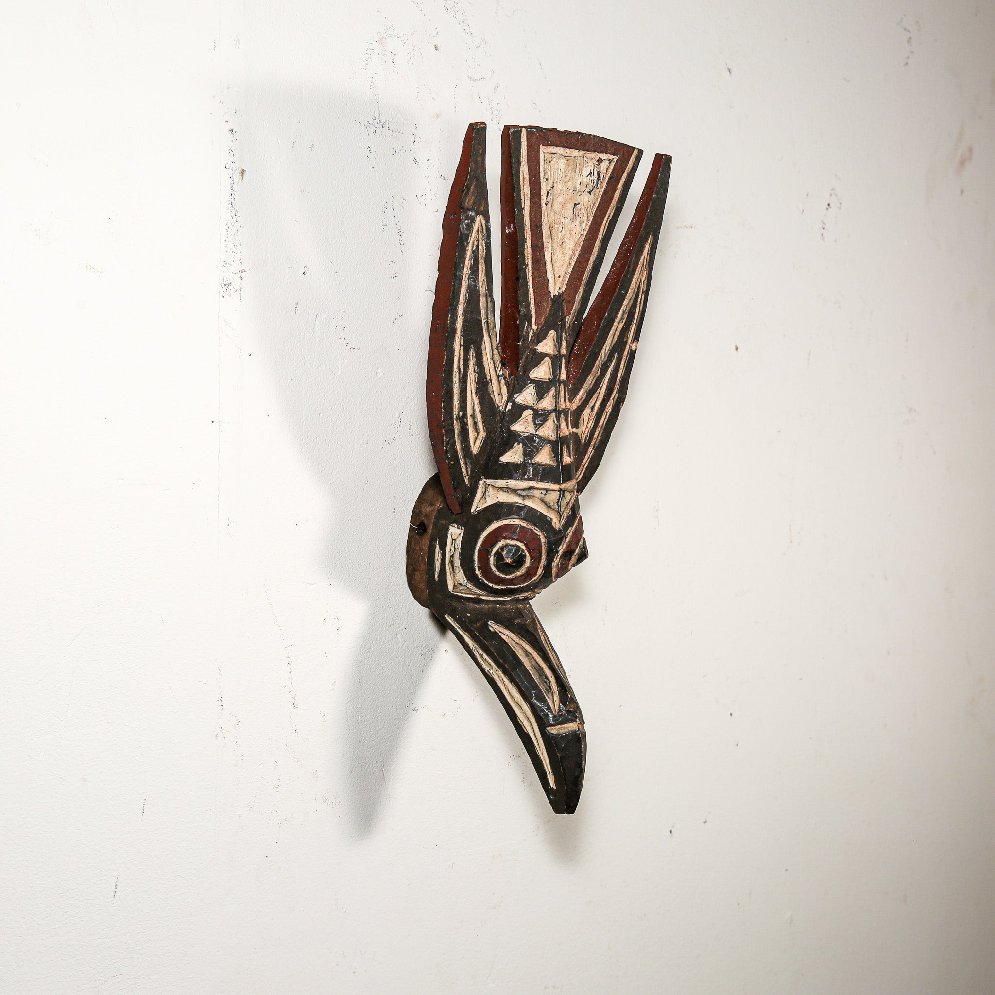 Decorative wooden mask with intricate carvings on a white background