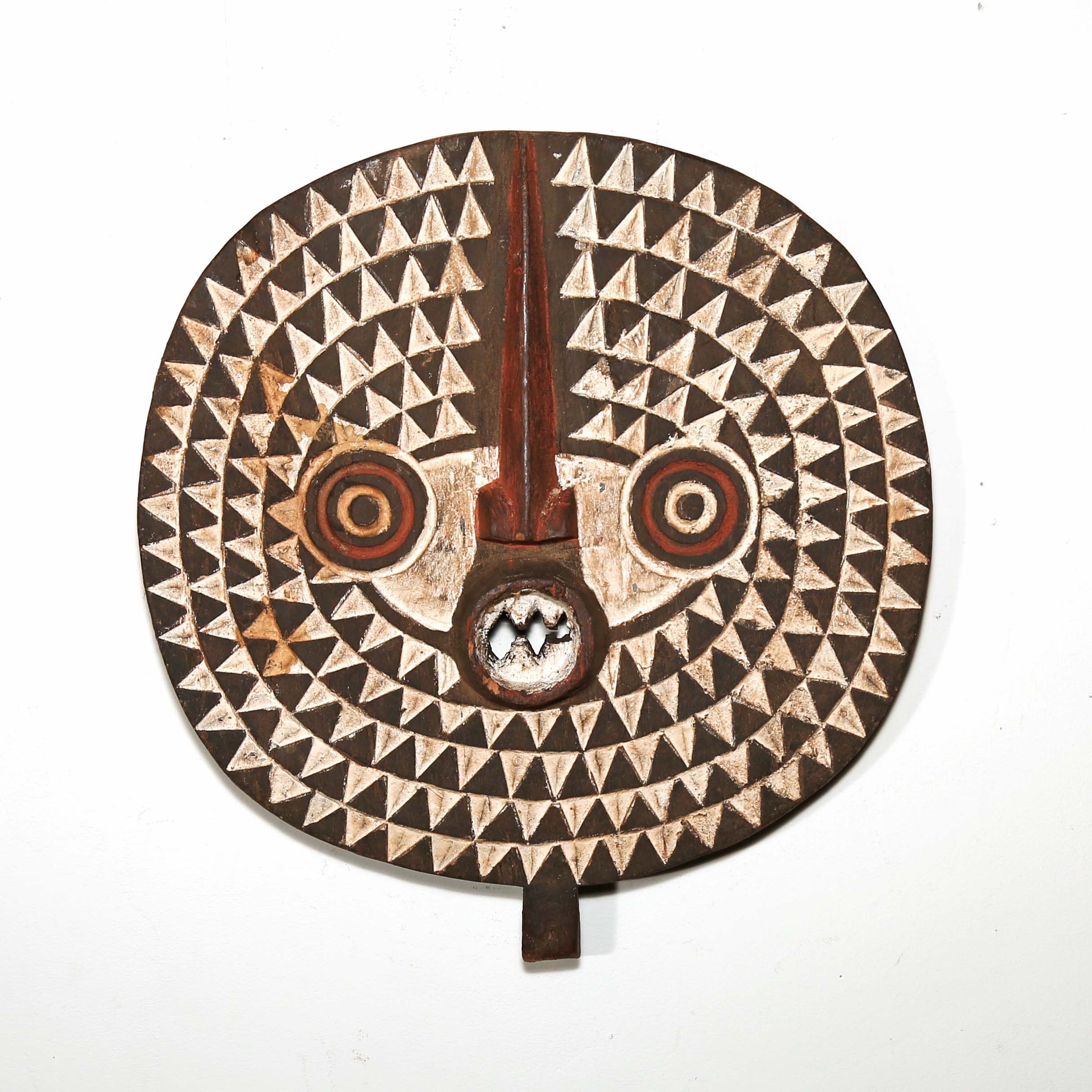 Round African mask on white wall