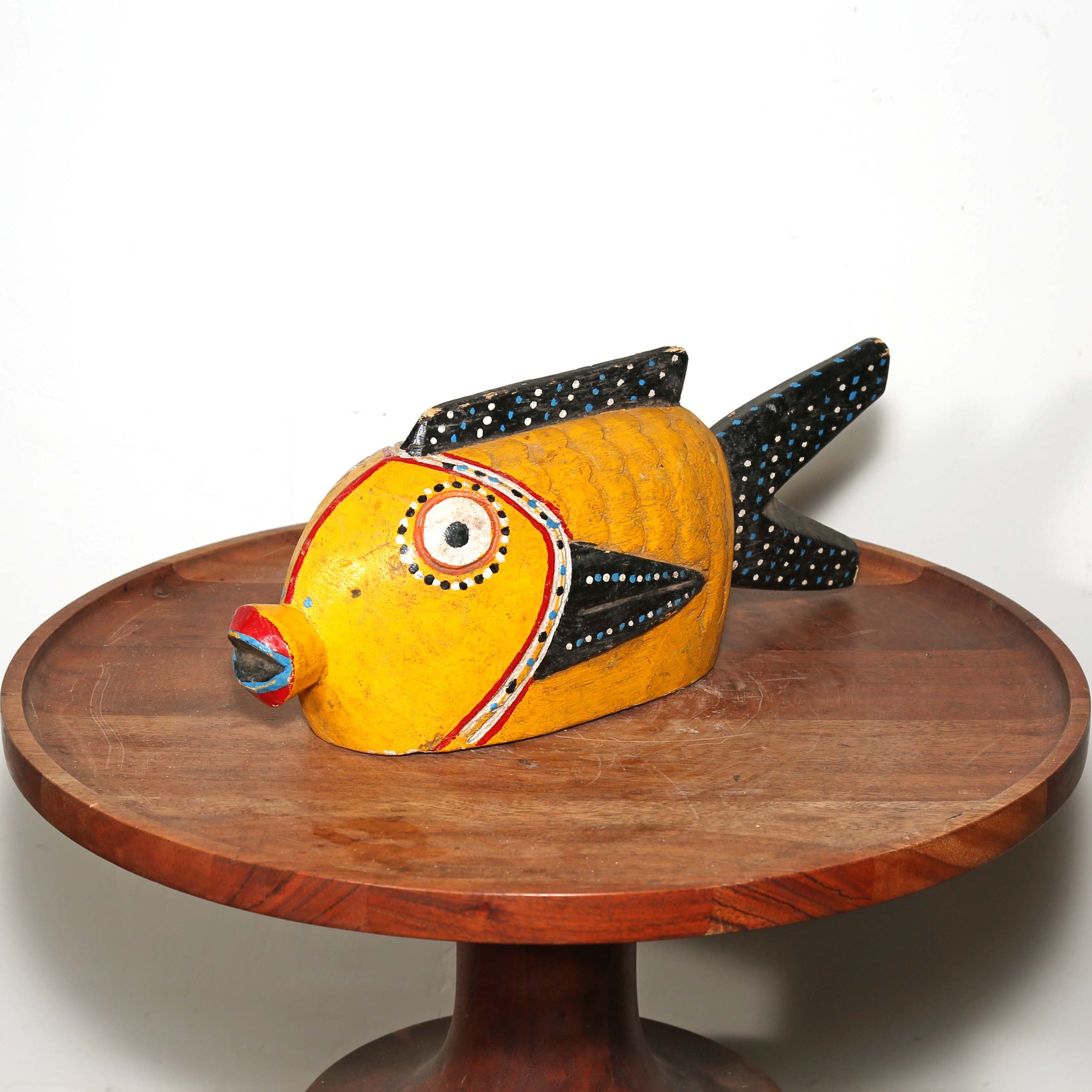 Yellow and Black Wood sculpture of a fish from Africa. Displayed on a table