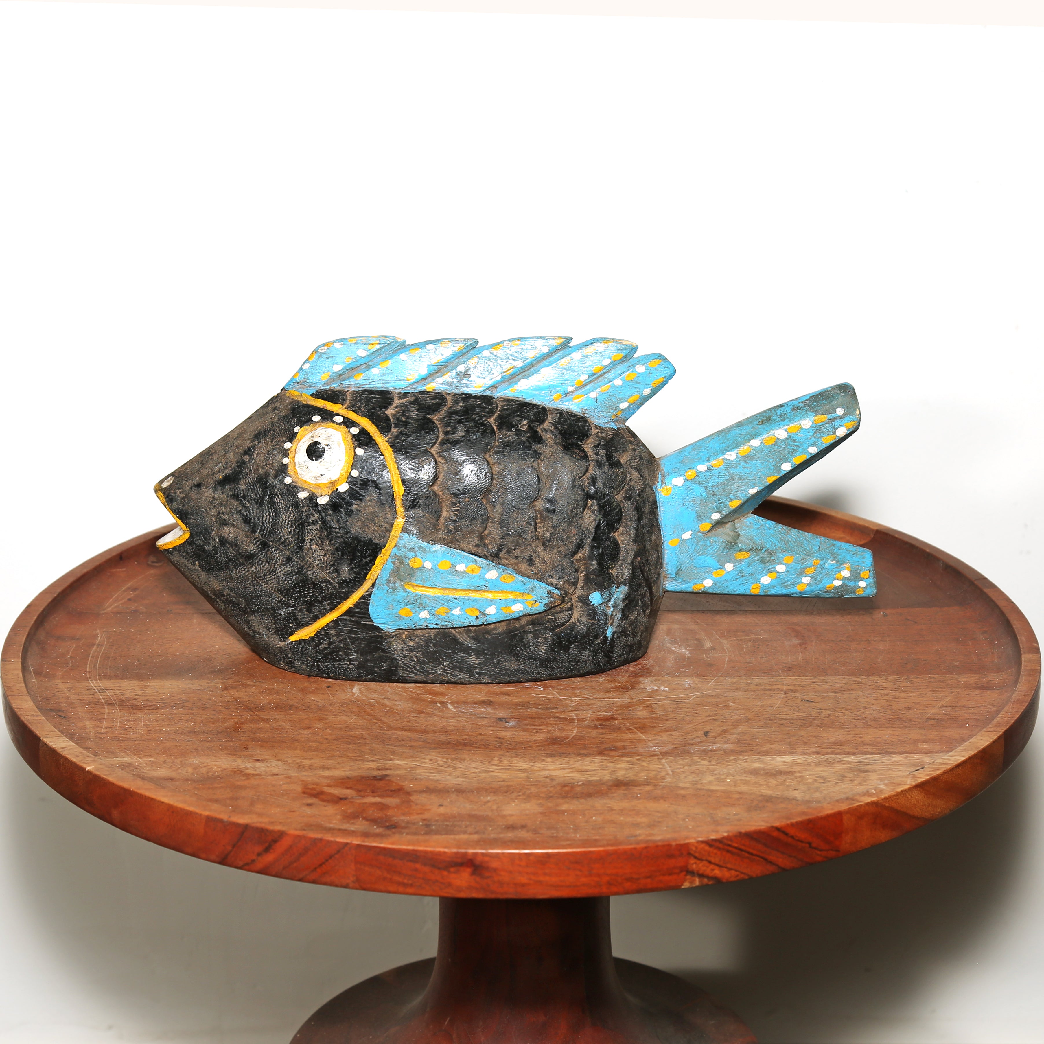 Black and blue painted wooden fish sculpture tribal African art. Displayed on a wooden side table for livingroom