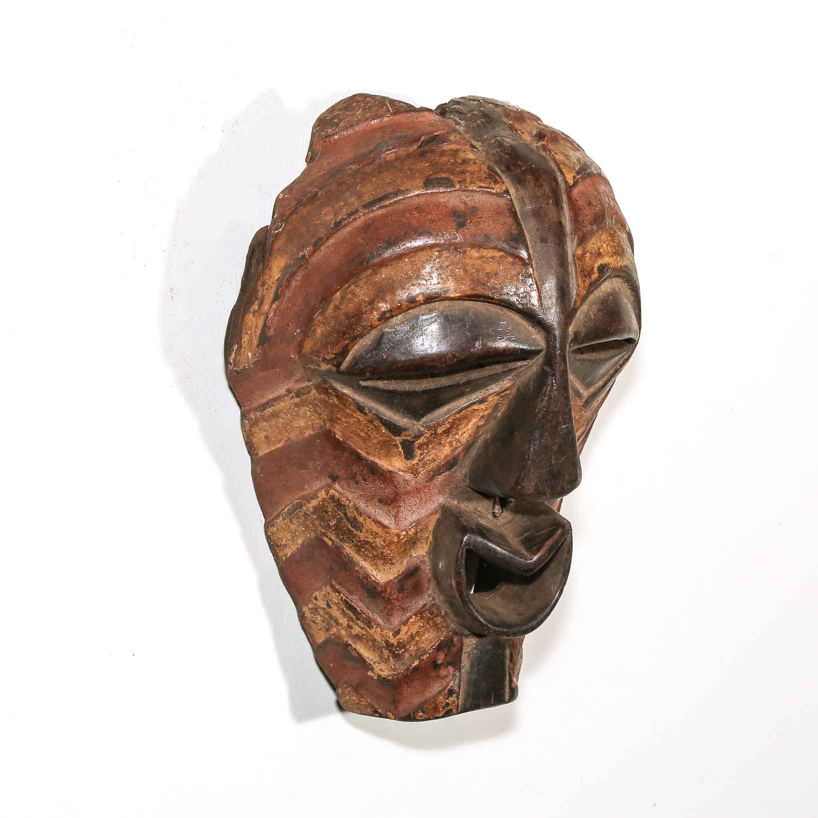 Wooden mask with intricate carvings on a white background