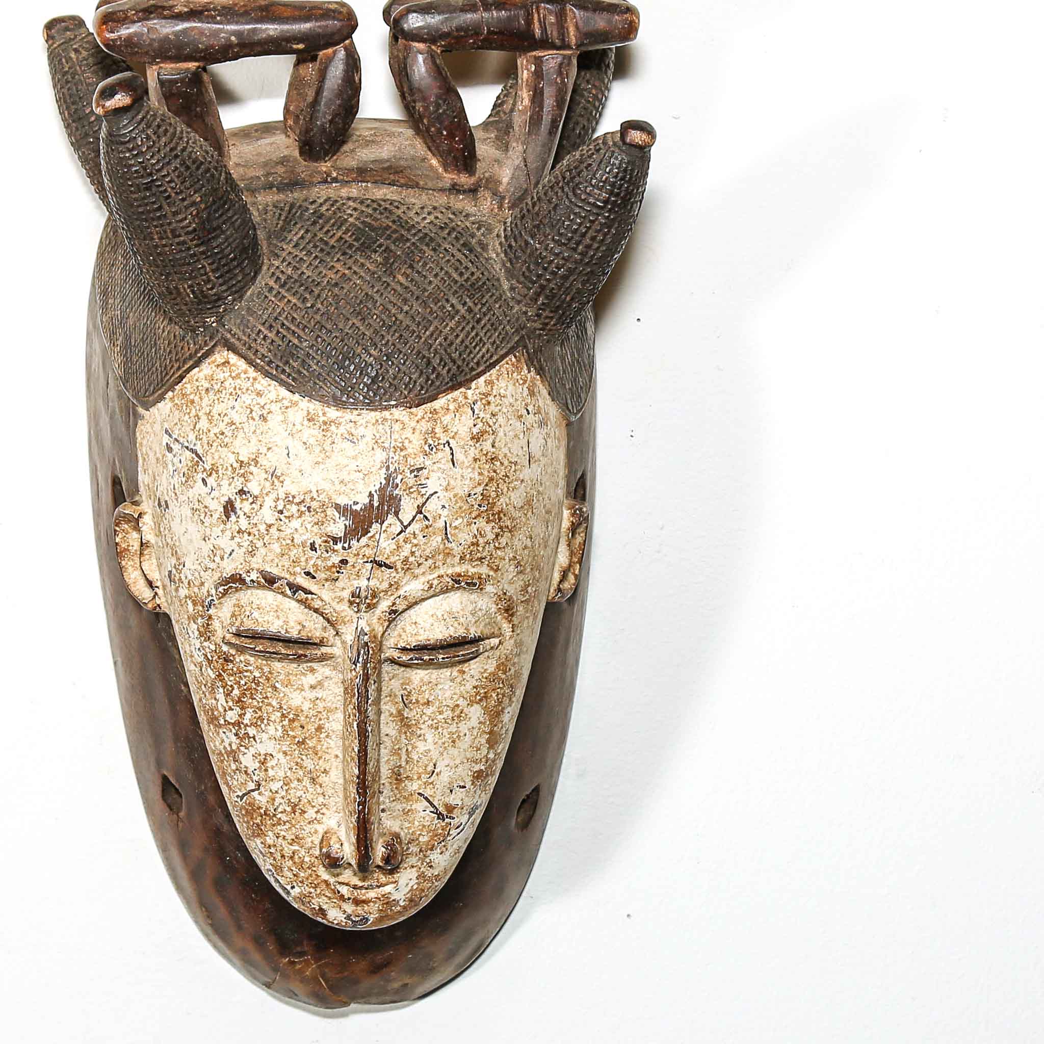close up of a Wooden  African mask with intricate carvings on a white background