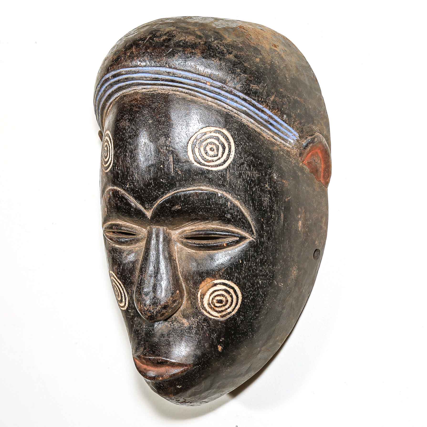 Black African-style wooden mask with intricate carvings on a white background