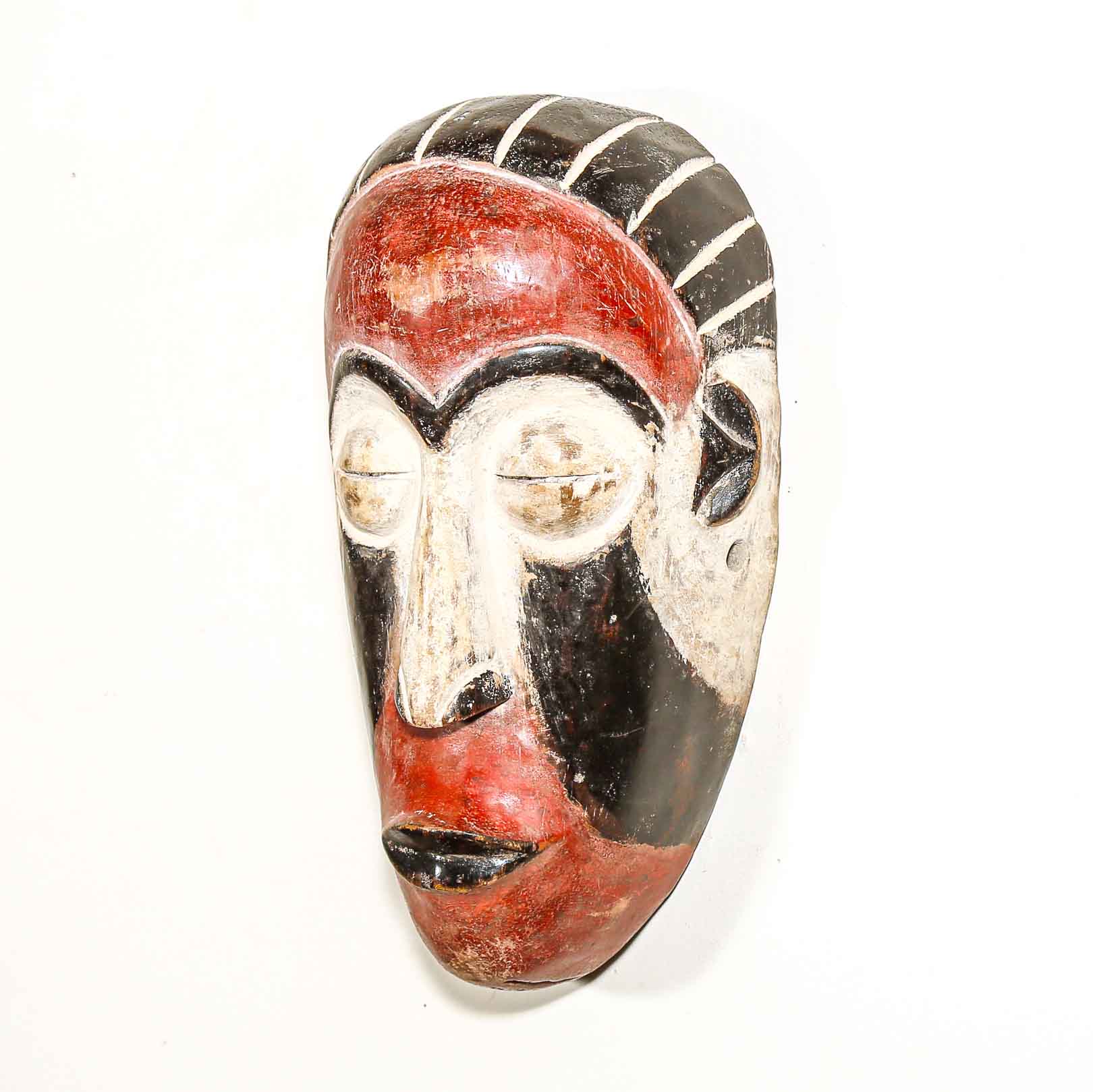 Ceremonial African wood mask with red, black, and white colors on a white background