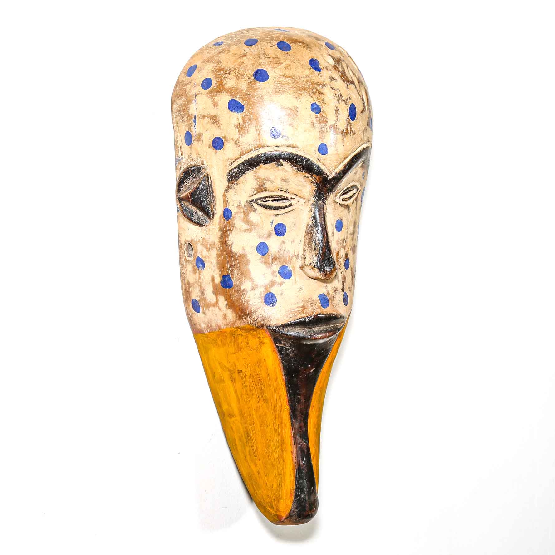 Carved wooden mask with blue polka dots on a white background by an artist in Africa