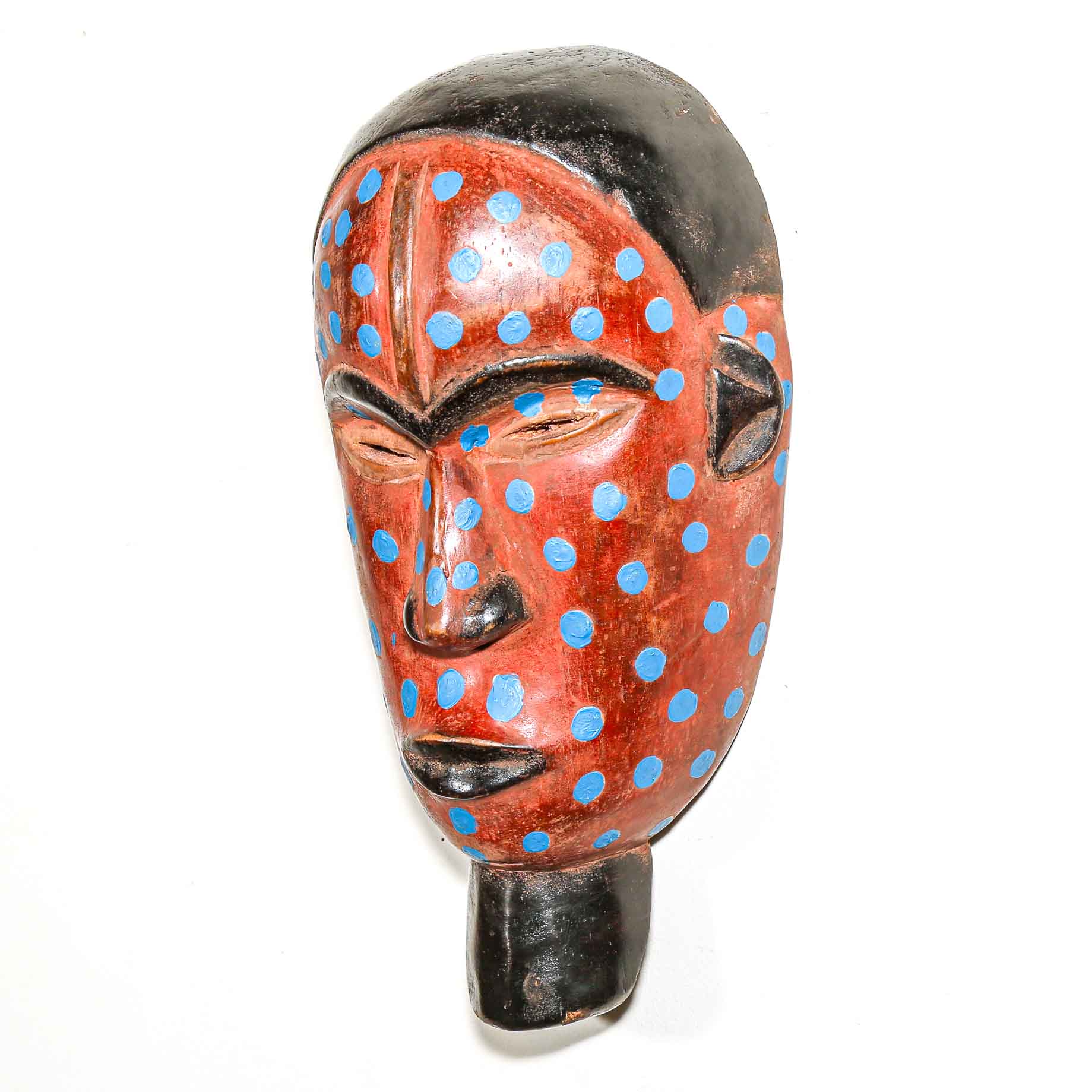 Wooden mask with red face and blue polka dots on a white background to hang on the wall