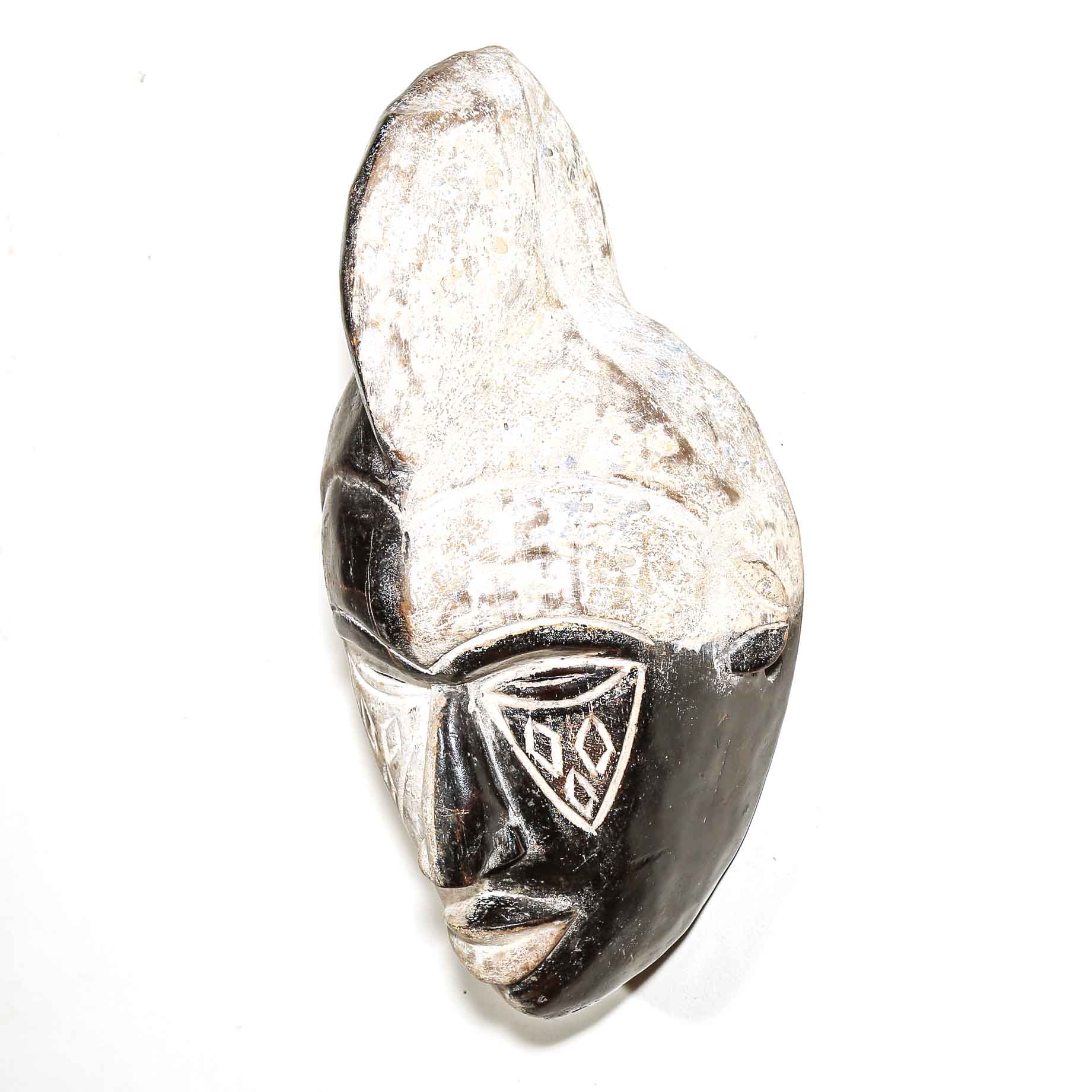 black African mask with carved white details on a white wall
