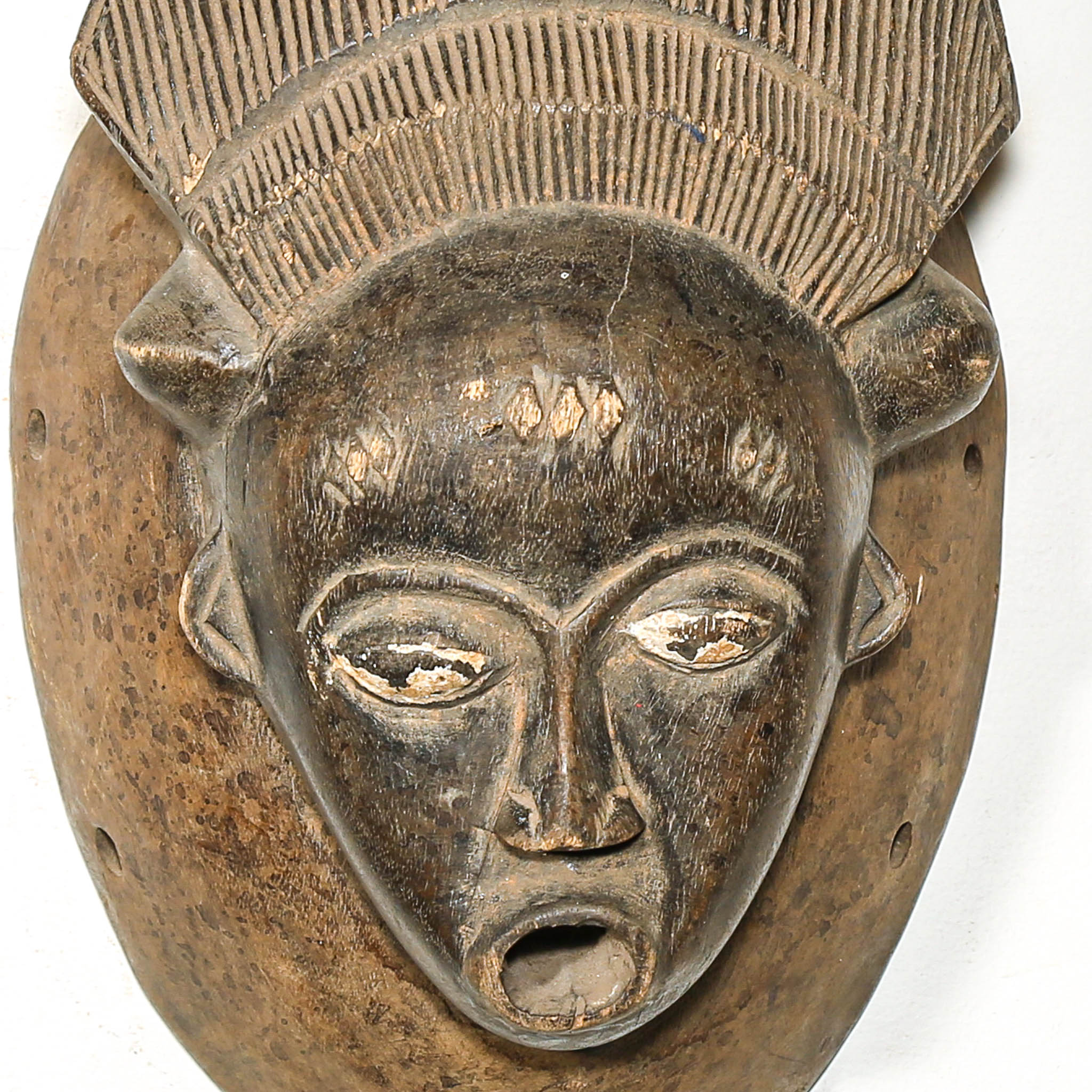 African art piece with a face mask on a white background