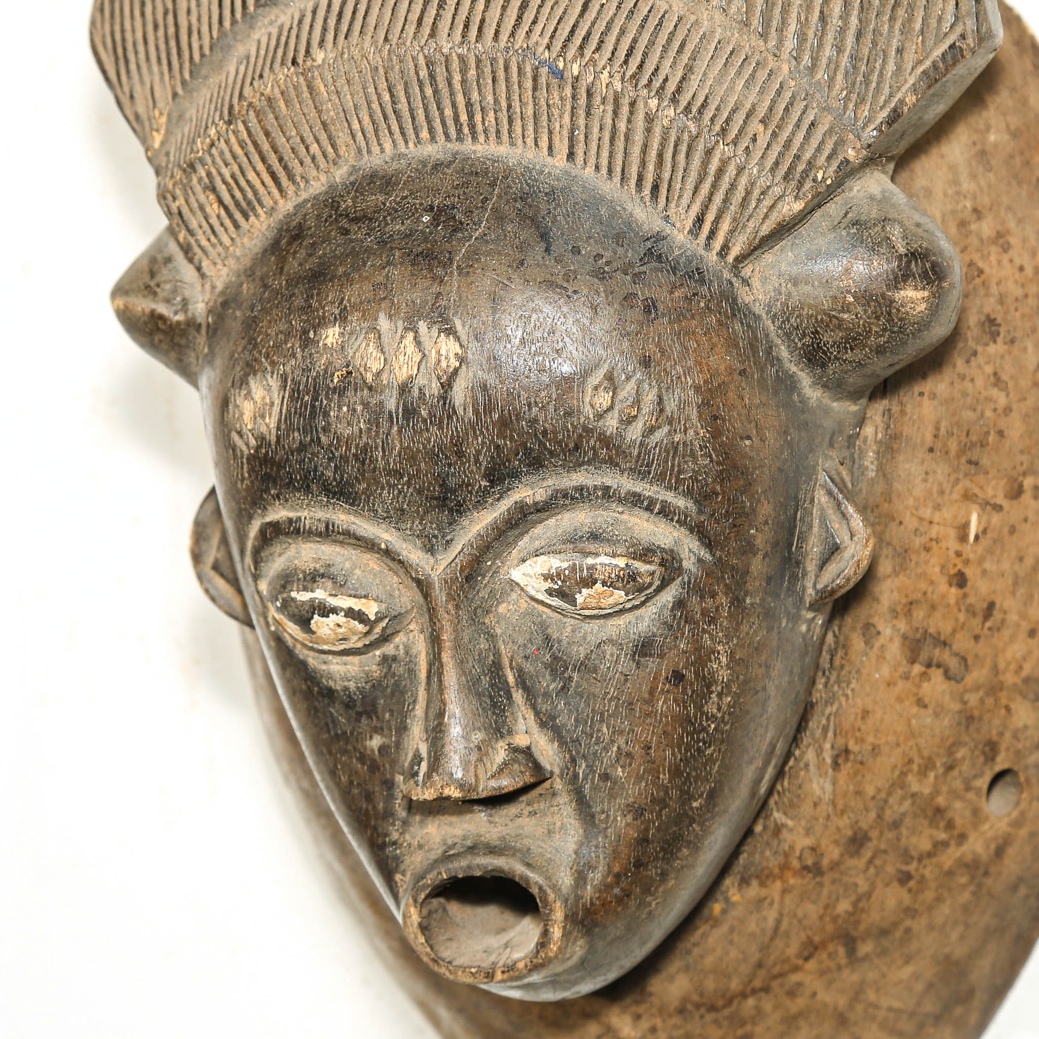 Close-up of an African mask with detailed carvings on a white background
