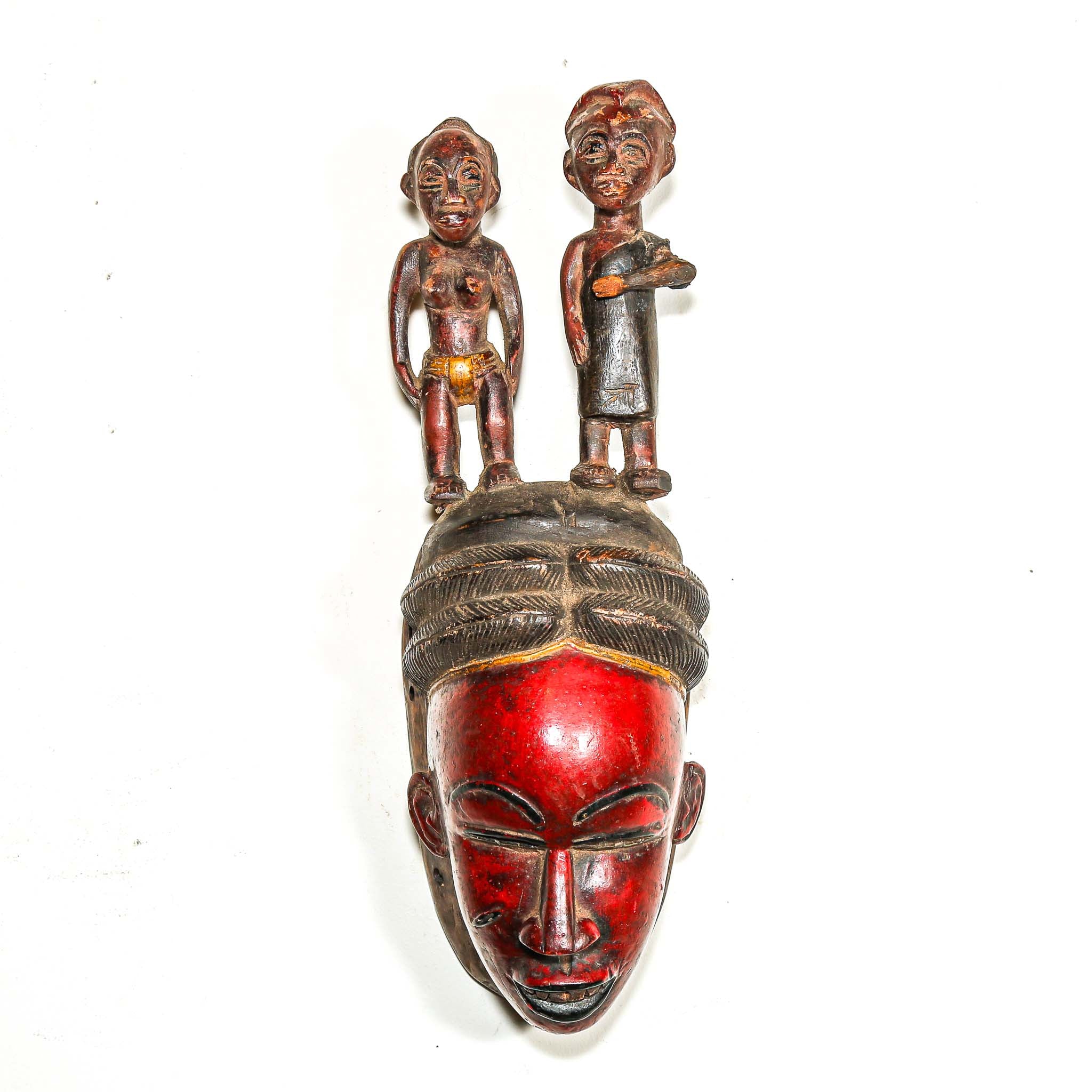 Red African handmade mask with two figures on top against a white background