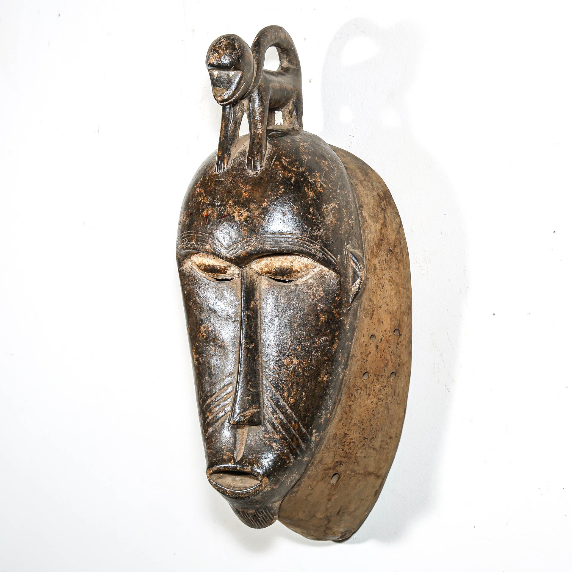 African mask with a detailed face and gorilla headdress on a white background