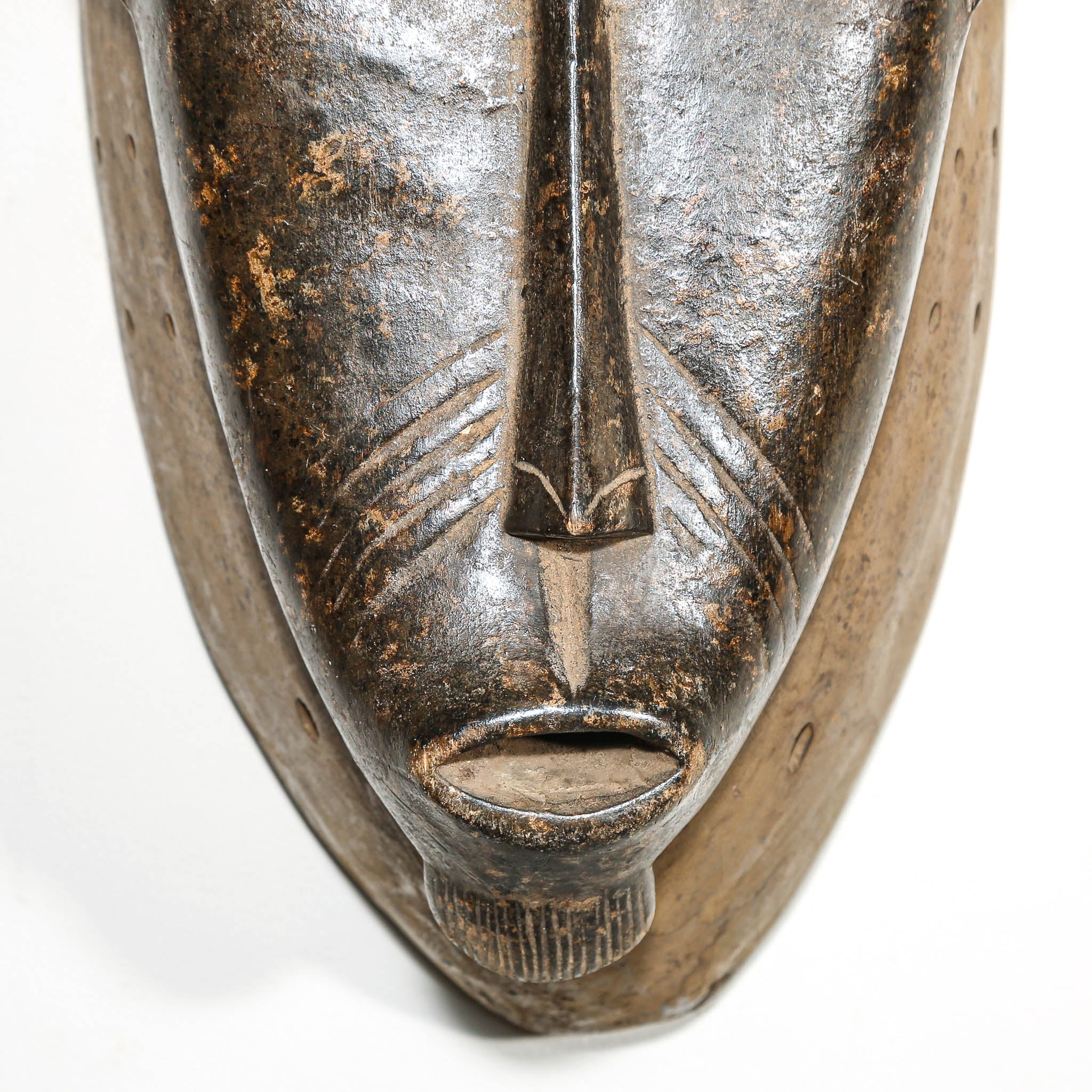Close-up of a metallic mask with detailed carvings on a white background
