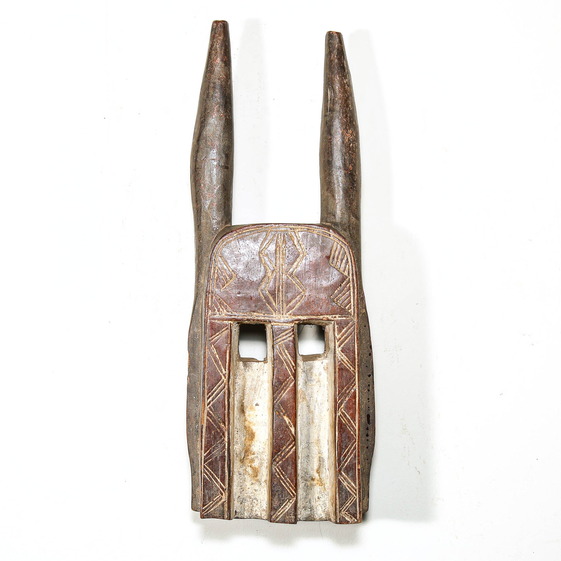 Decorative wooden mask from Mali with long horns on a white background