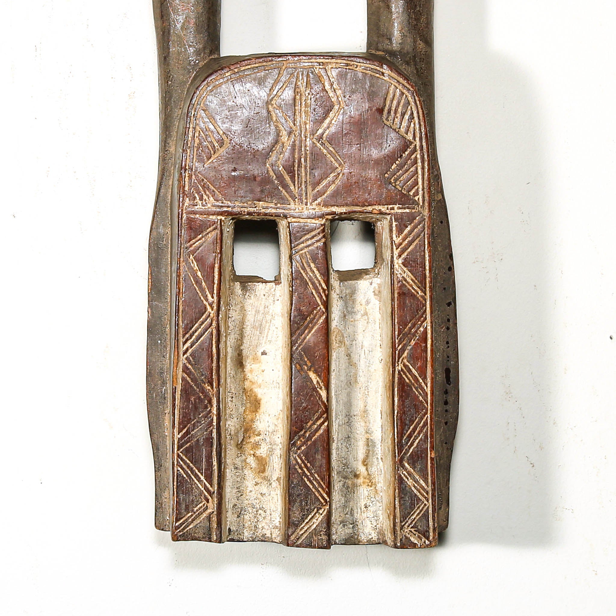 Decorative wooden mask from Mali with long horns on a white background close up