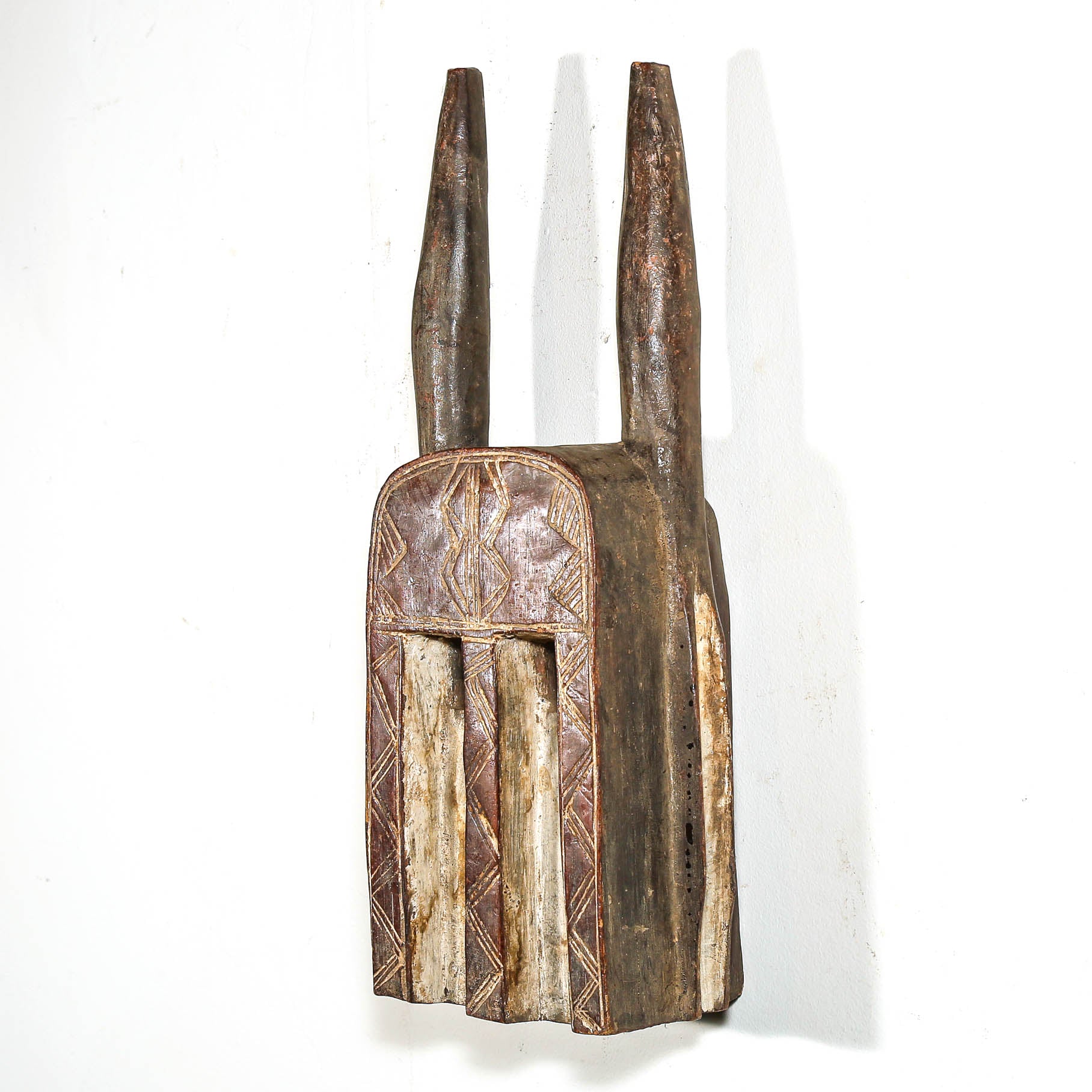Wooden african mask with intricate carvings on a white background