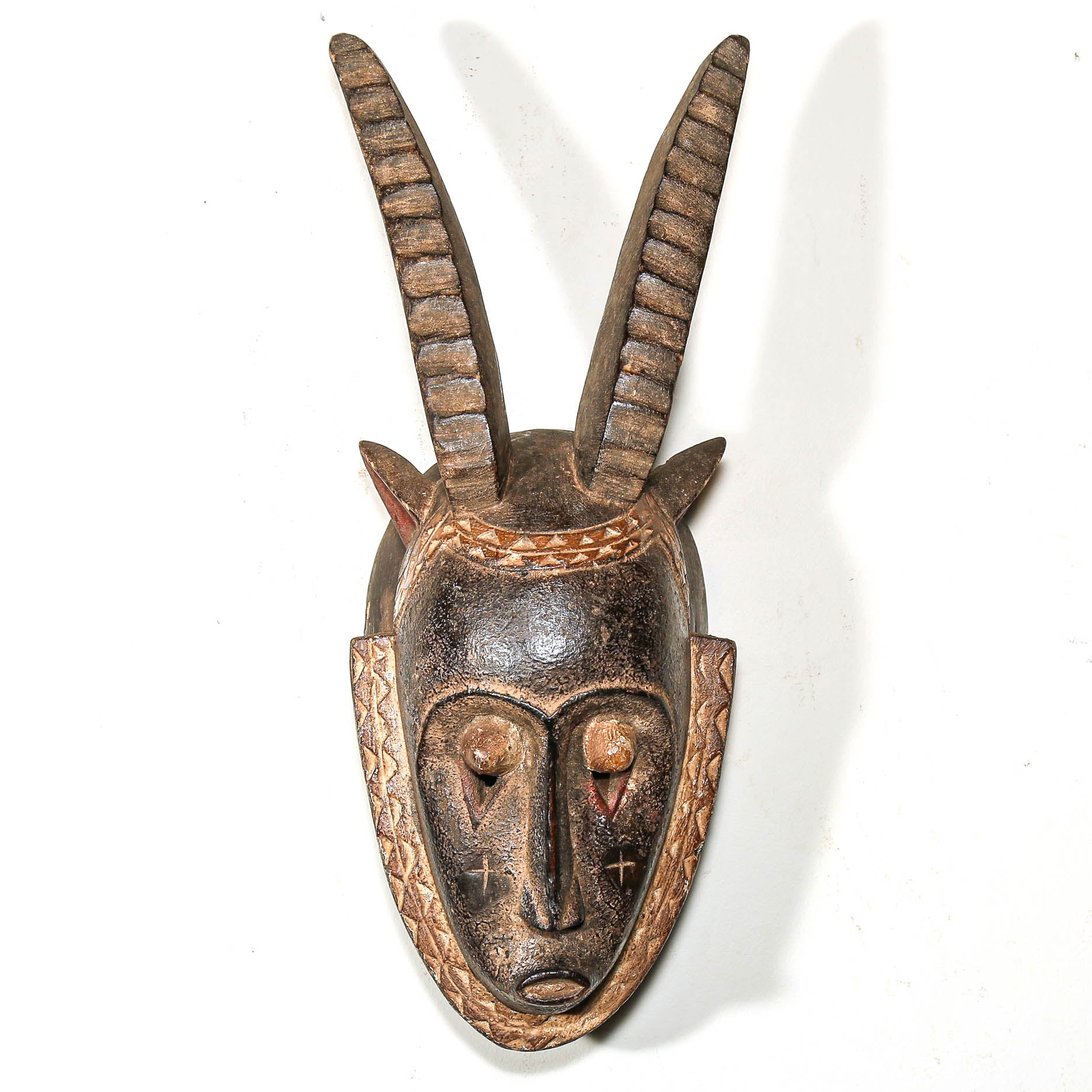 Wooden mask with goat horns on a white background