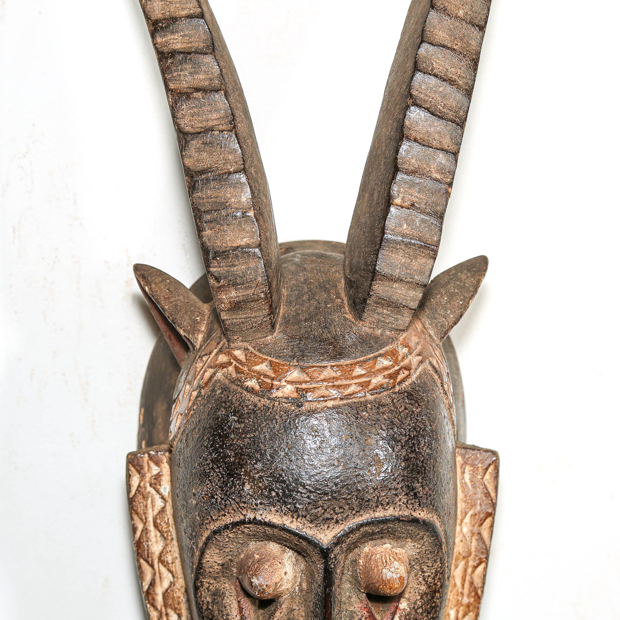 Wooden mask with antelope horns on a white background