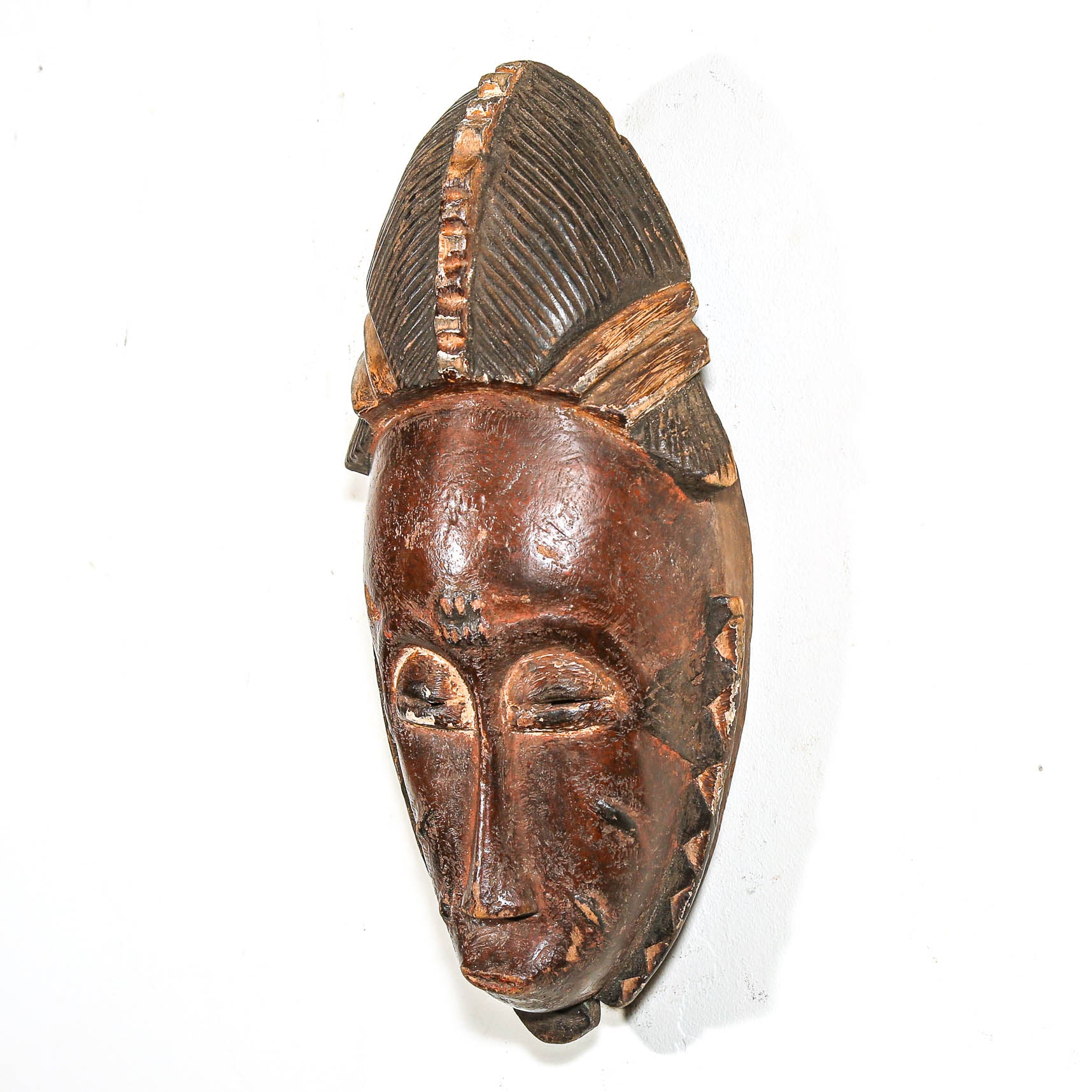 Wooden mask with intricate carvings on a white background