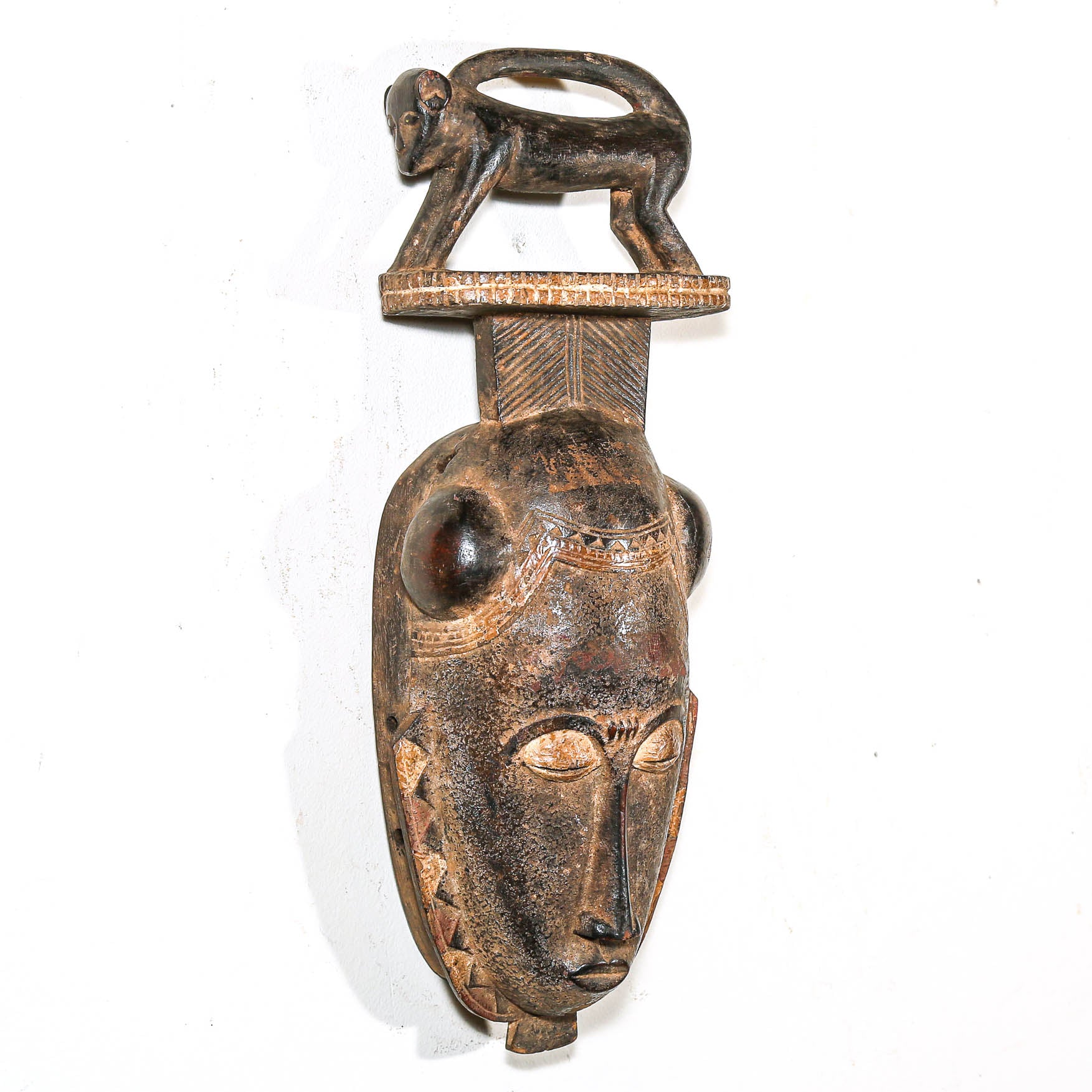 Decorative mask with a face and monkey figure on a white background