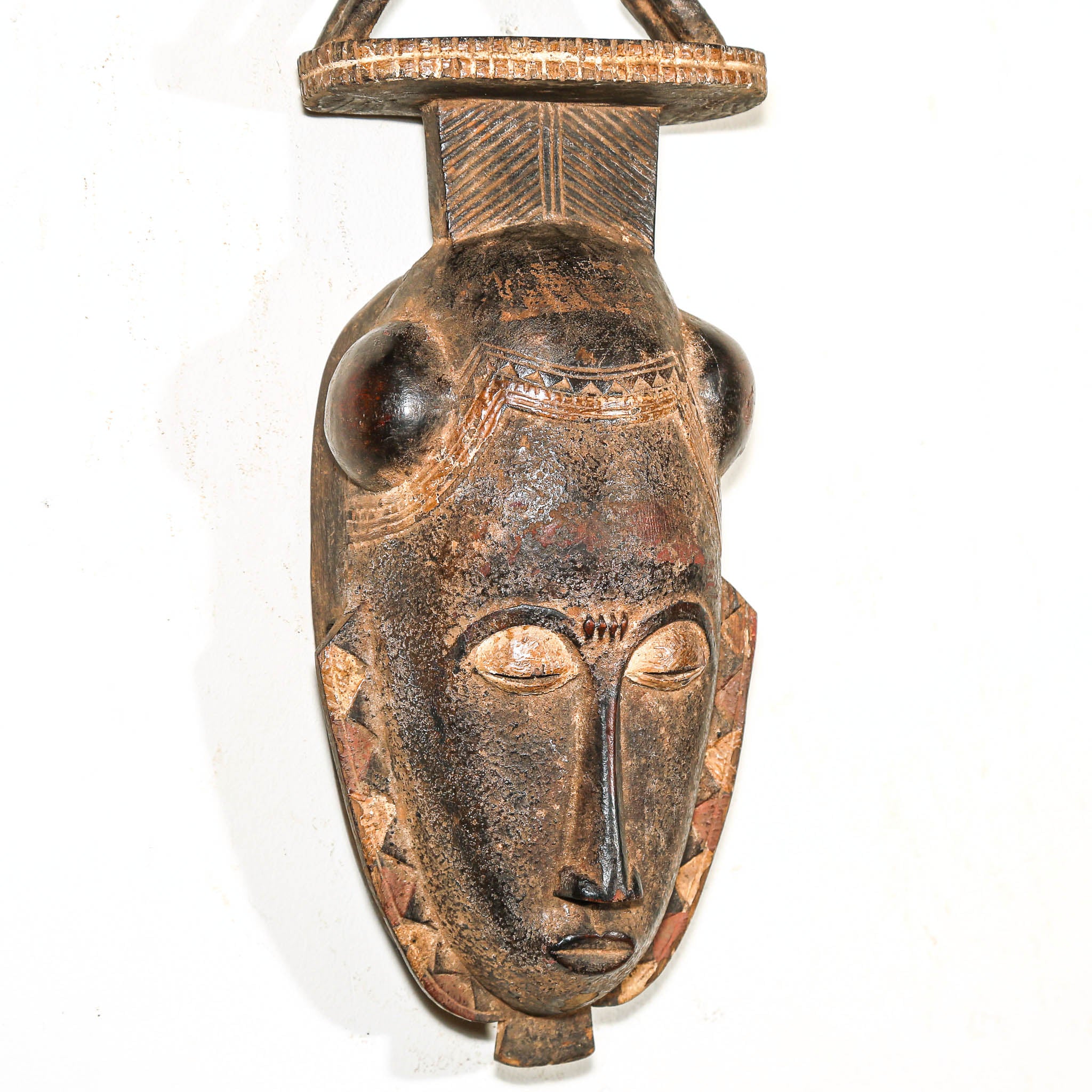 African mask with detailed carvings on a white background