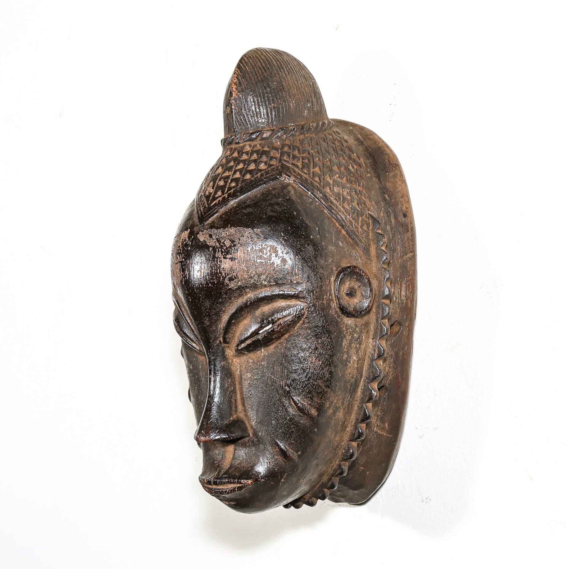 Black Wooden mask from Africa with intricate carvings on a white background