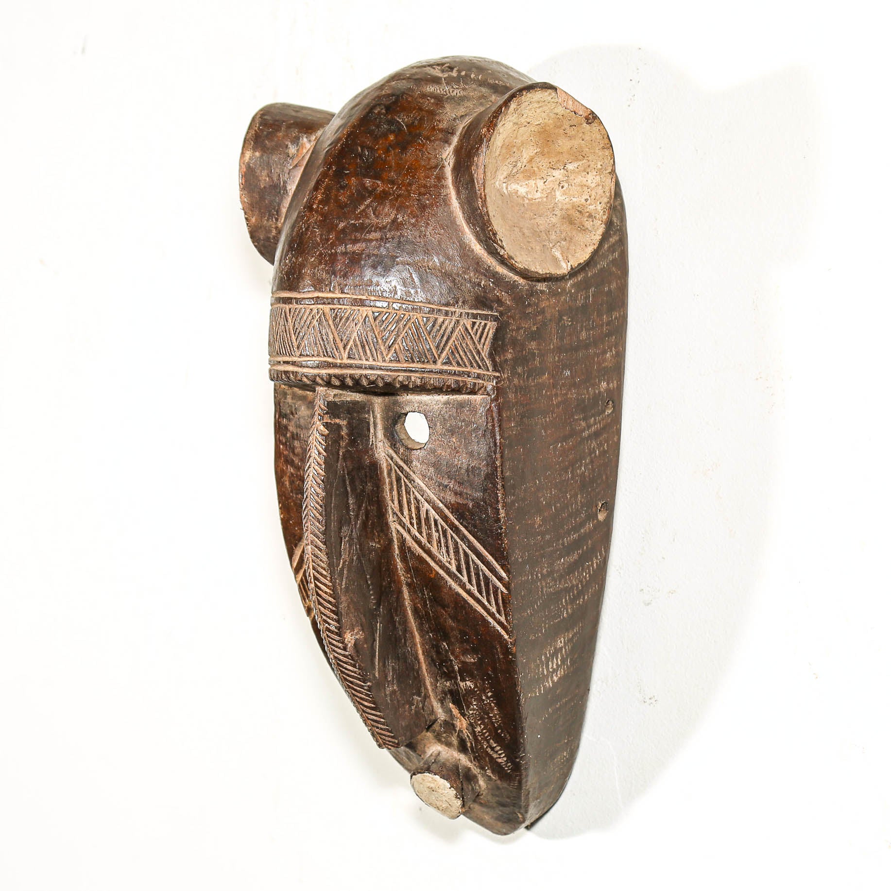 Brown black african Wooden mask with carvings on a white background