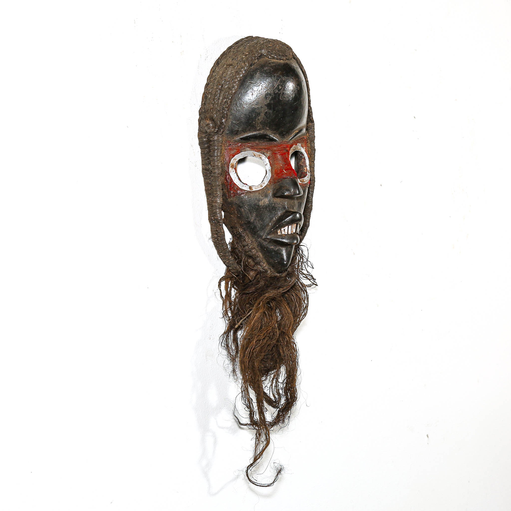 Traditional mask with wooden face and braided hair on a white background