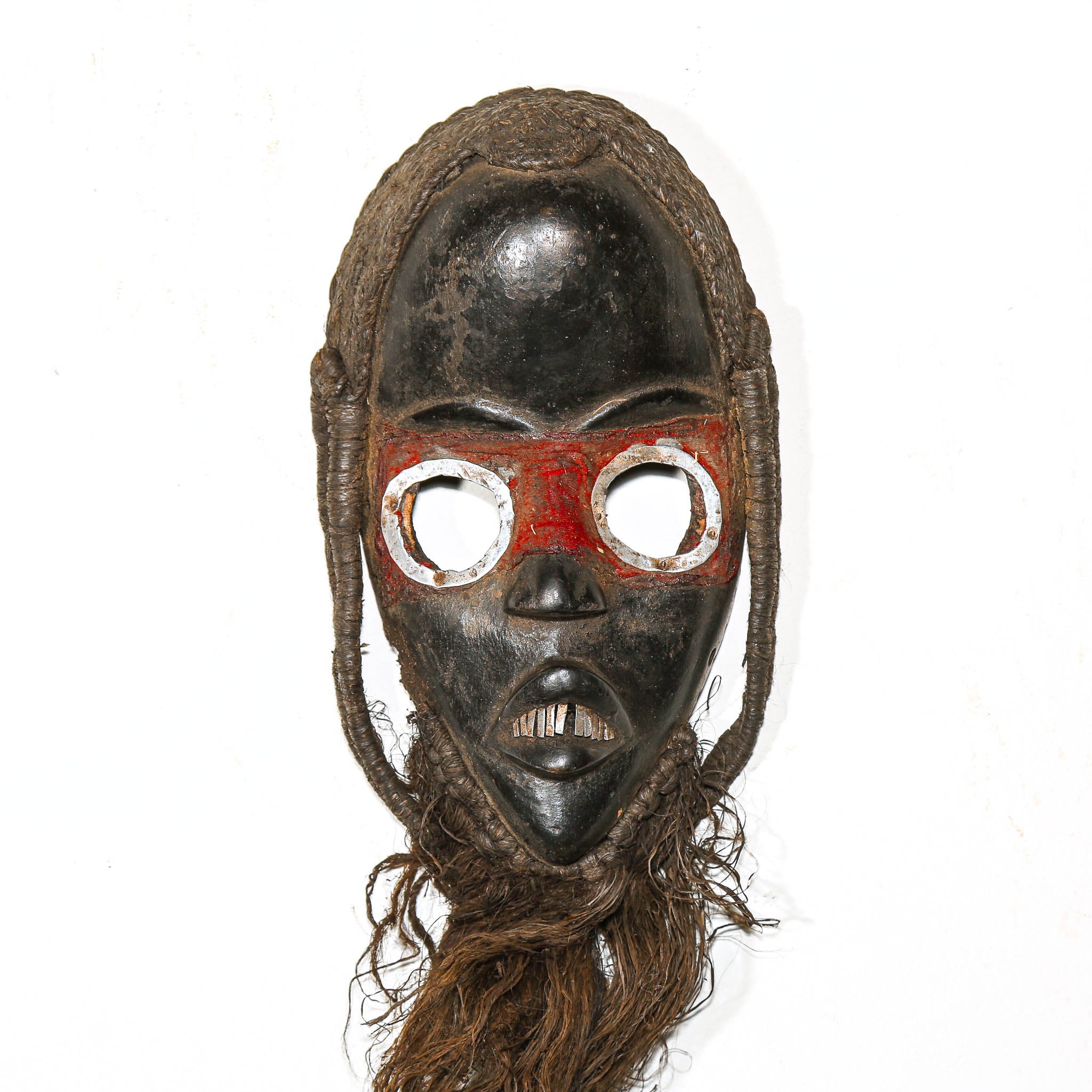 Traditional mask with black face, red eyes, and brown hair on a white background