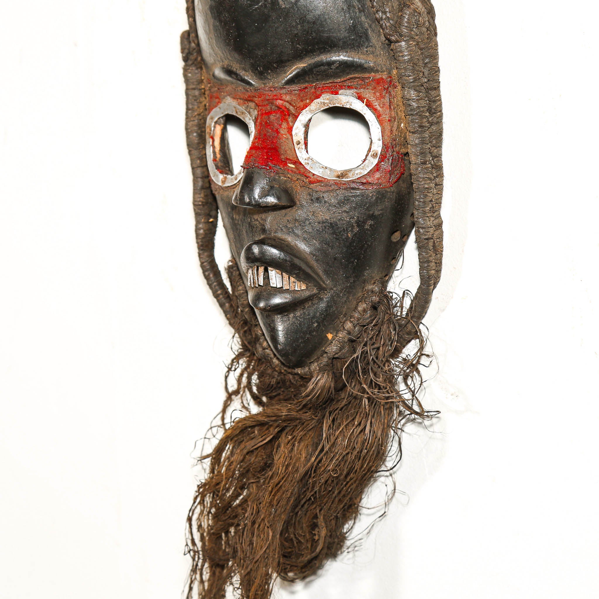 Traditional African mask with red and silver accents on a white background