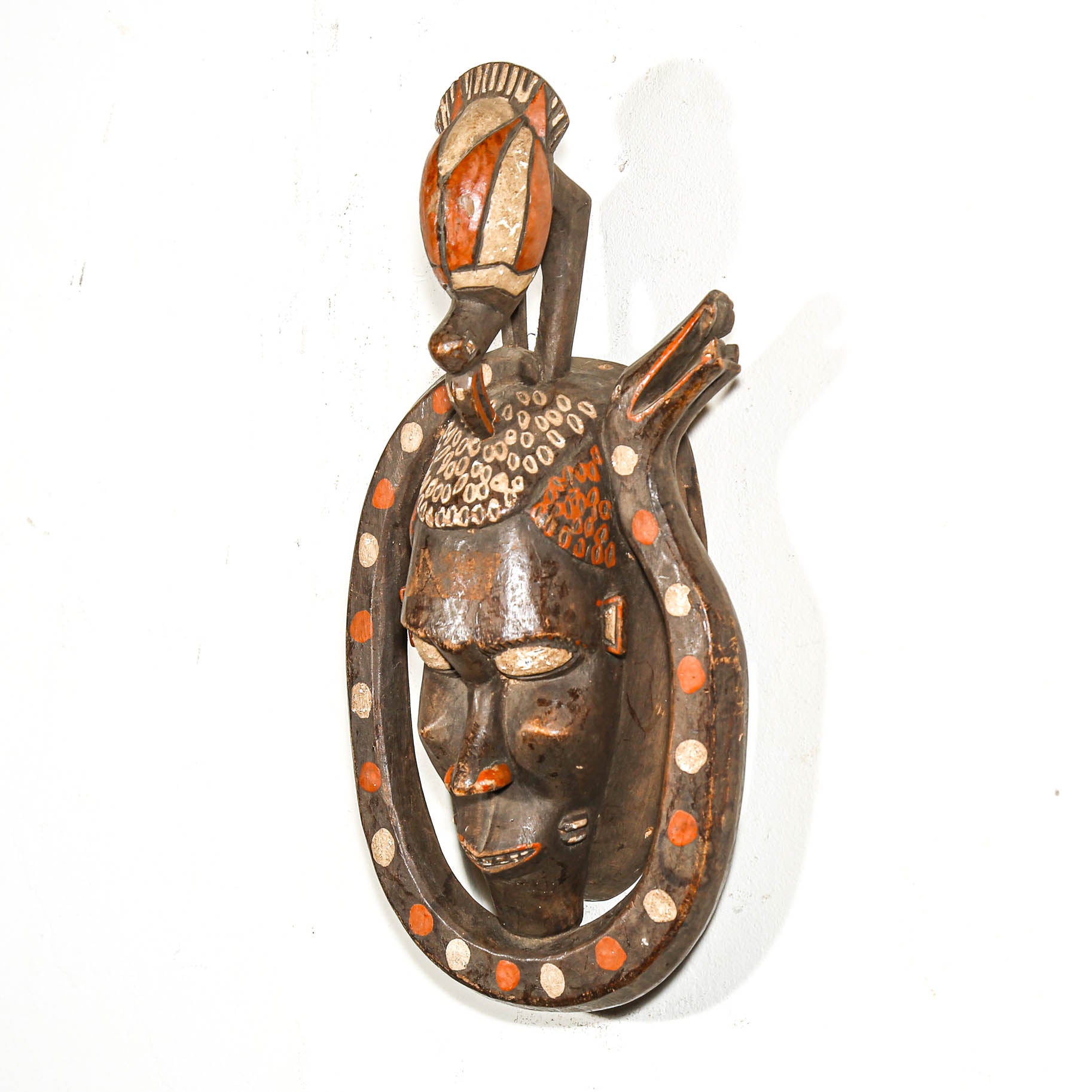 Decorative wall mask with intricate carved bird designs on a white background