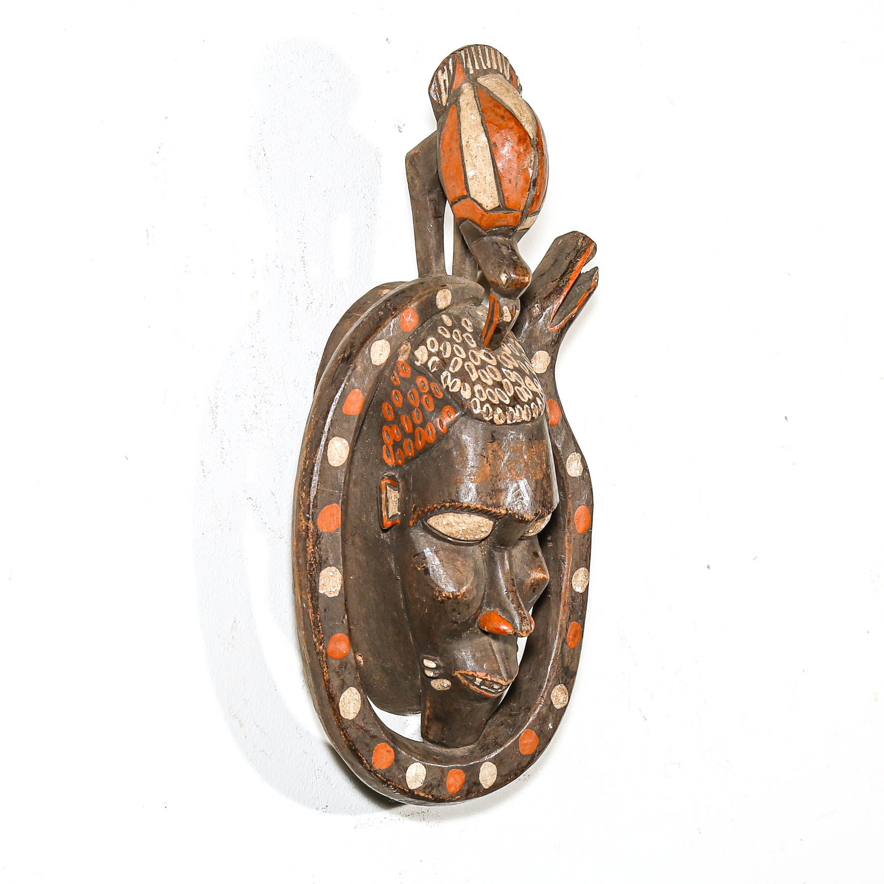 Black African mask with snake and bird on a white wall