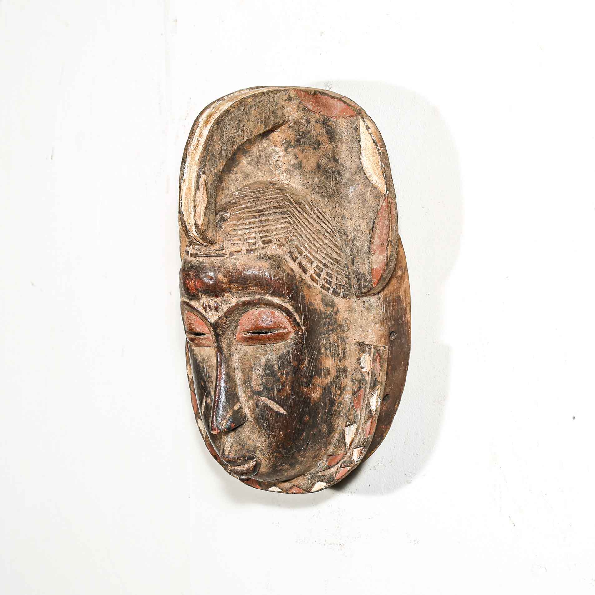 Wooden mask with carved facial features on a white background