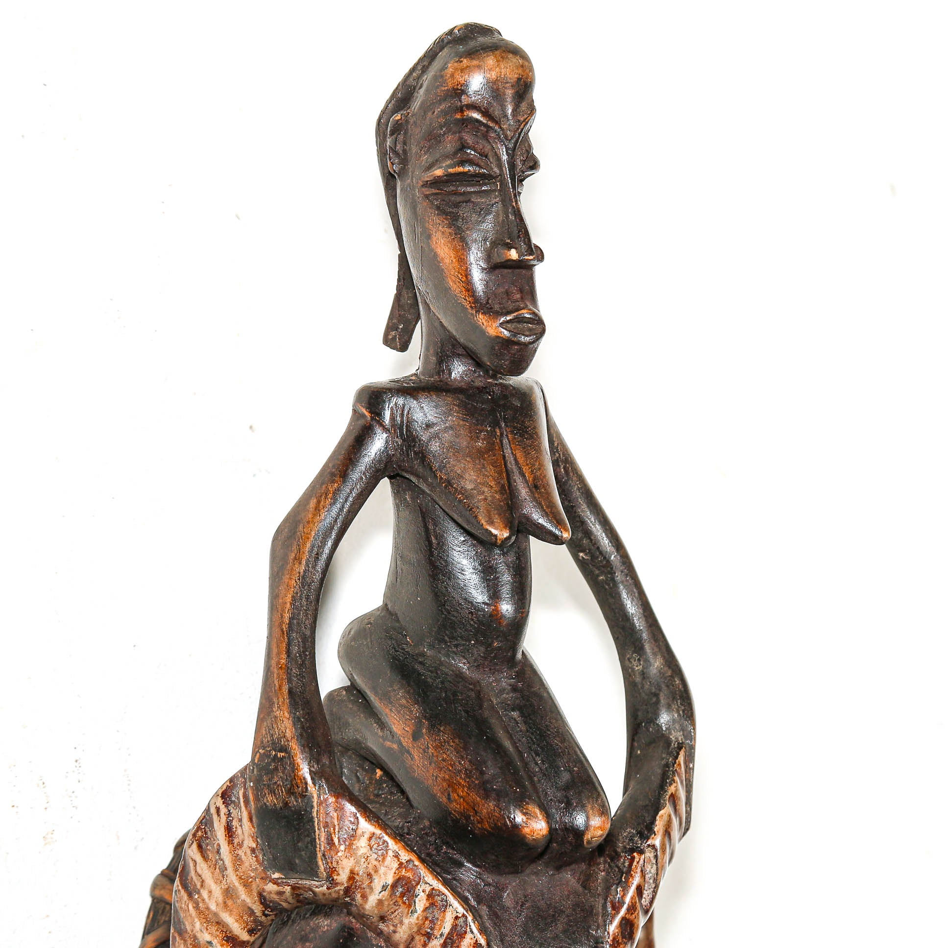 Detail of Wooden sculpture of a seated figure on a white background