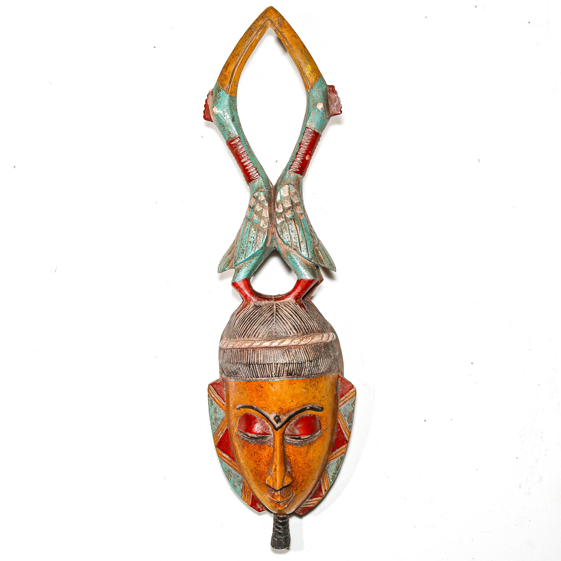 Colorful wooden mask with bird motifs on a white wall