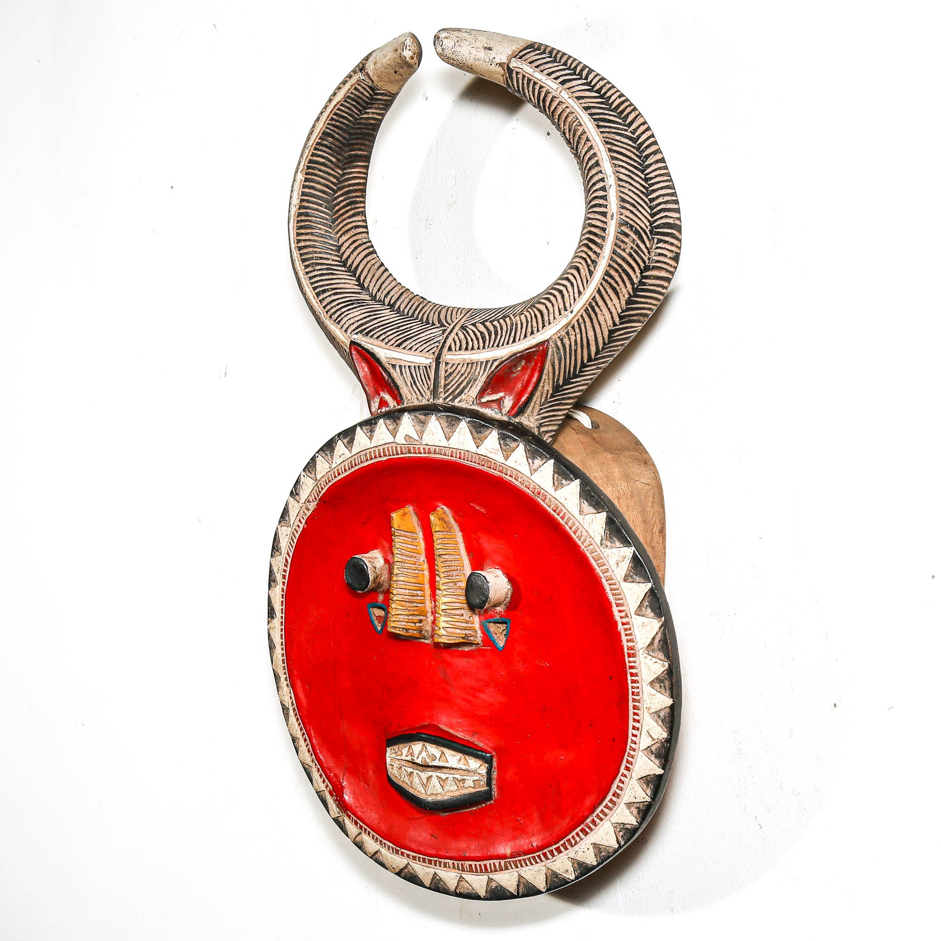 Decorative flat African mask with red center and metallic accents on a white background